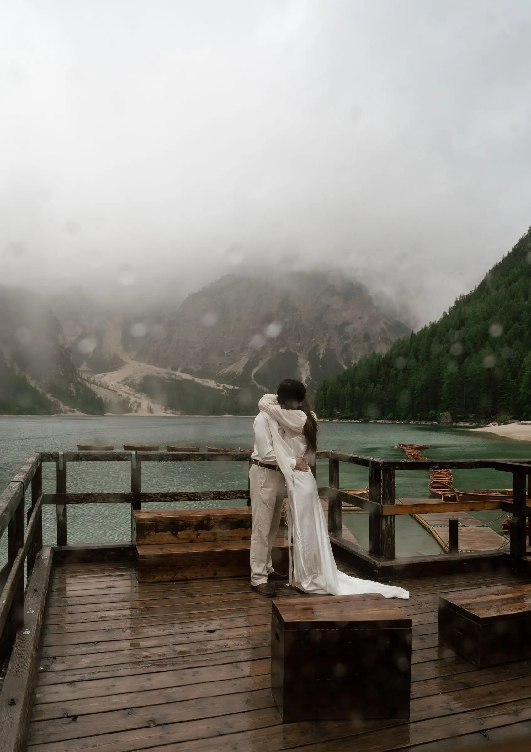 Couple embracing on the rainy boathouse terrace above the lake