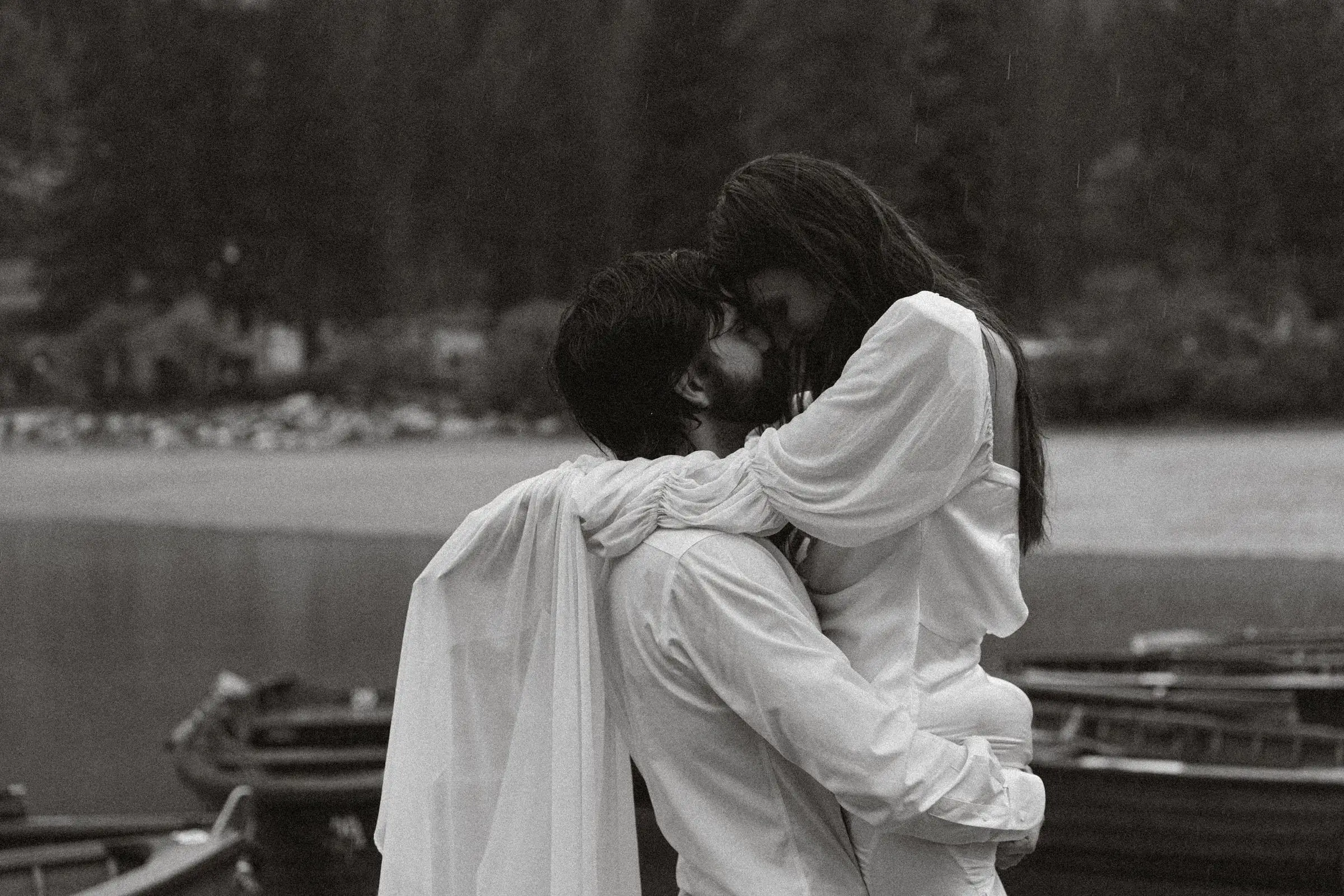 Black and white photo of the couple embracing on the jetty