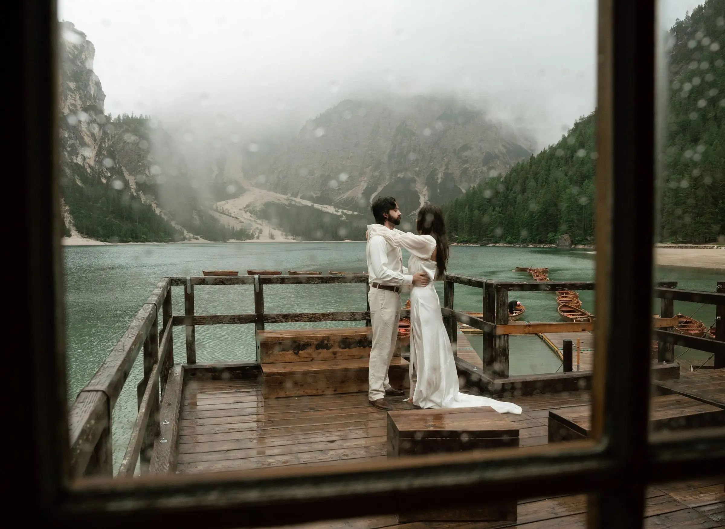 Couple embracing on the terrace, framed by the boathouse window