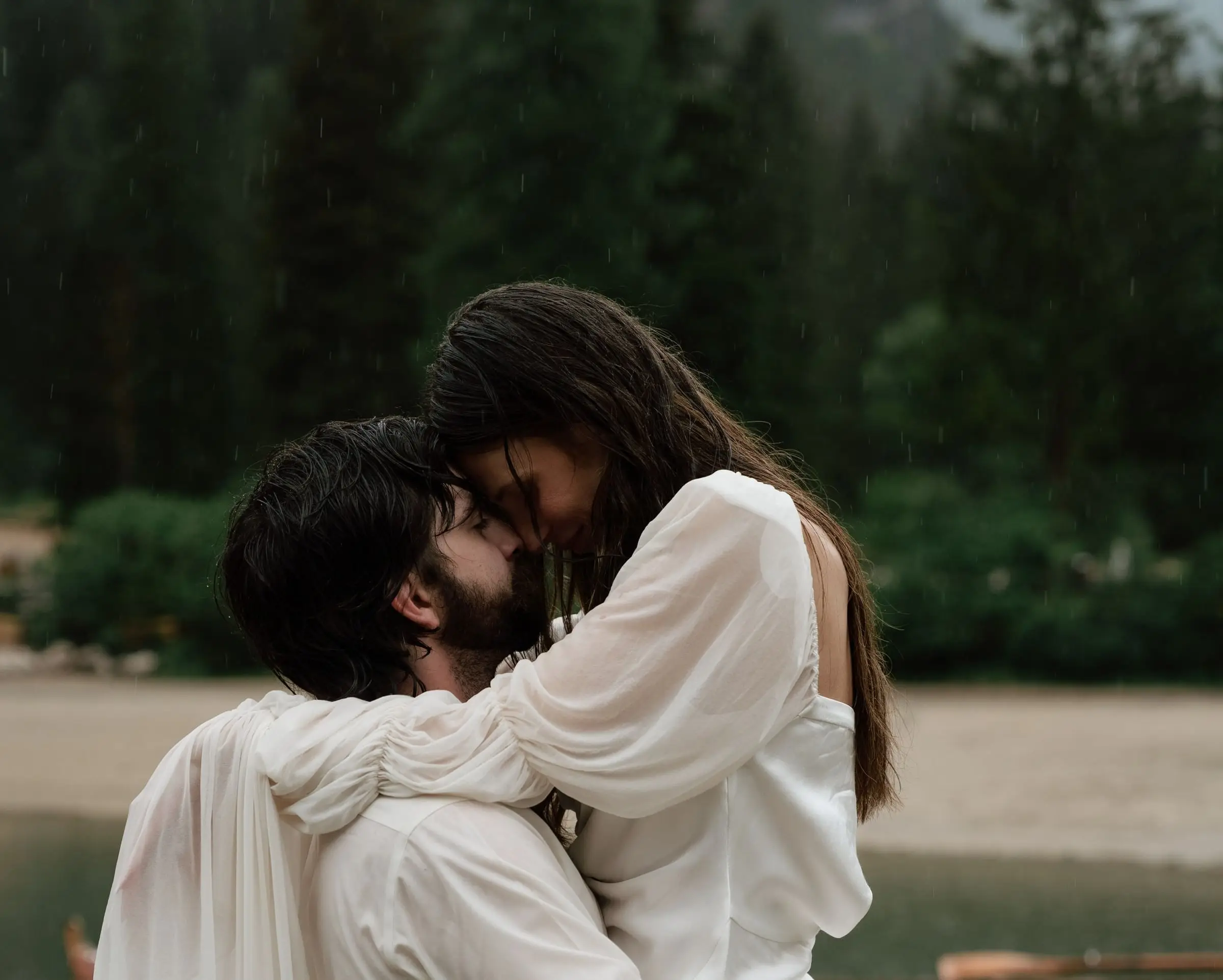 Couple forehead to forehead in the rain by the lake
