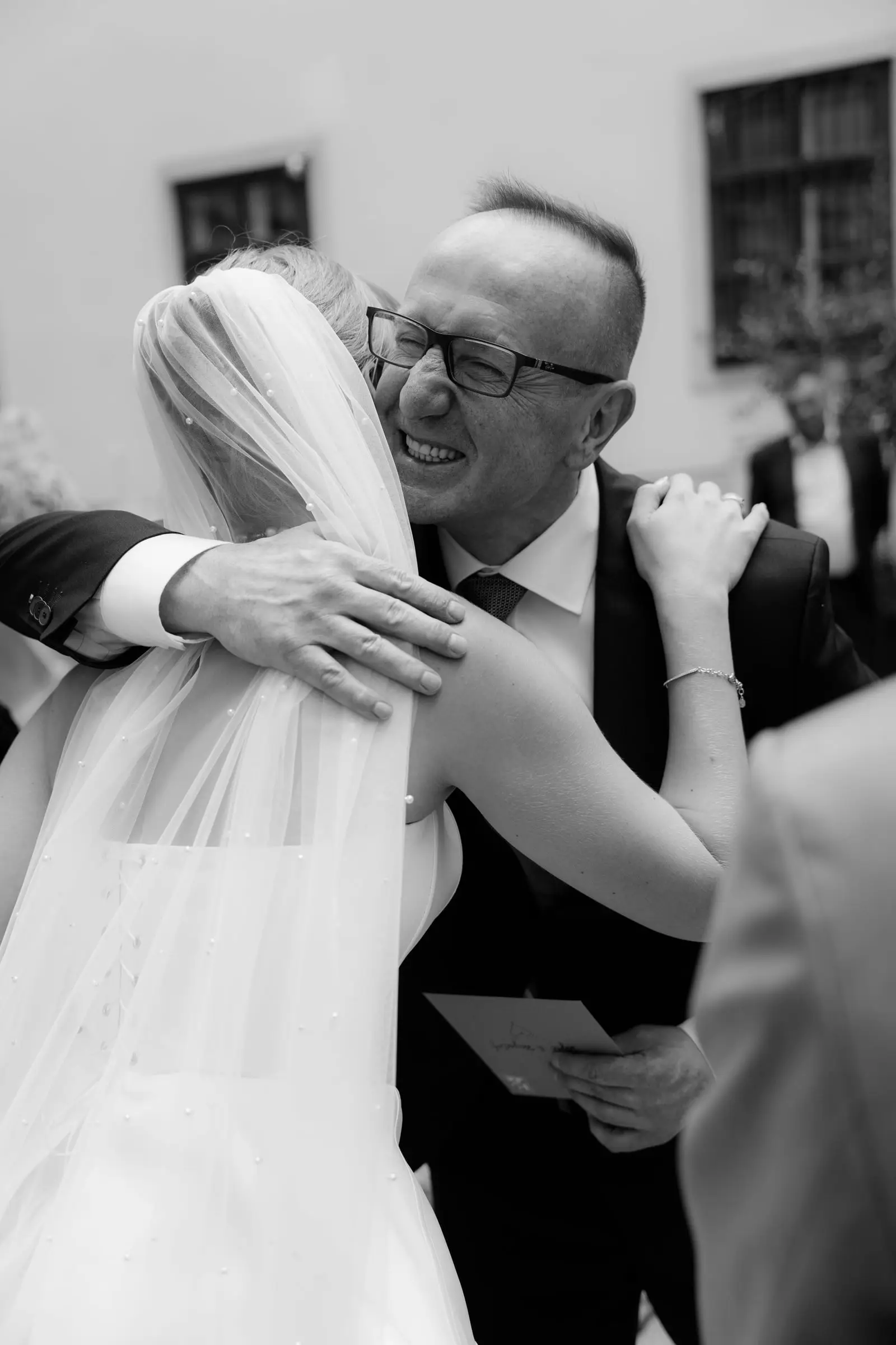 Black and white photo of the bride hugging a guest after the church ceremony