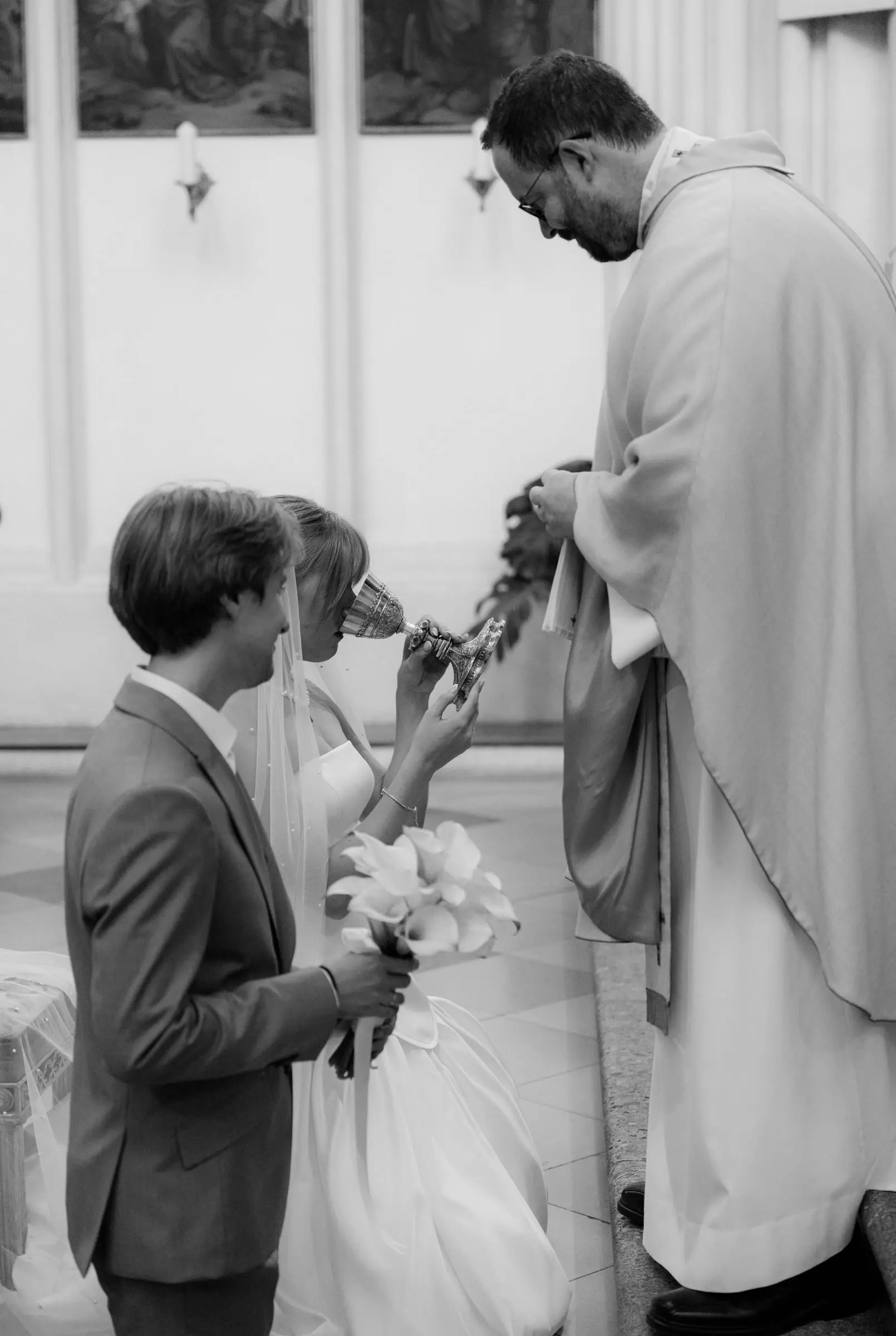 Black and white photo of the priest blessing the couple at the altar