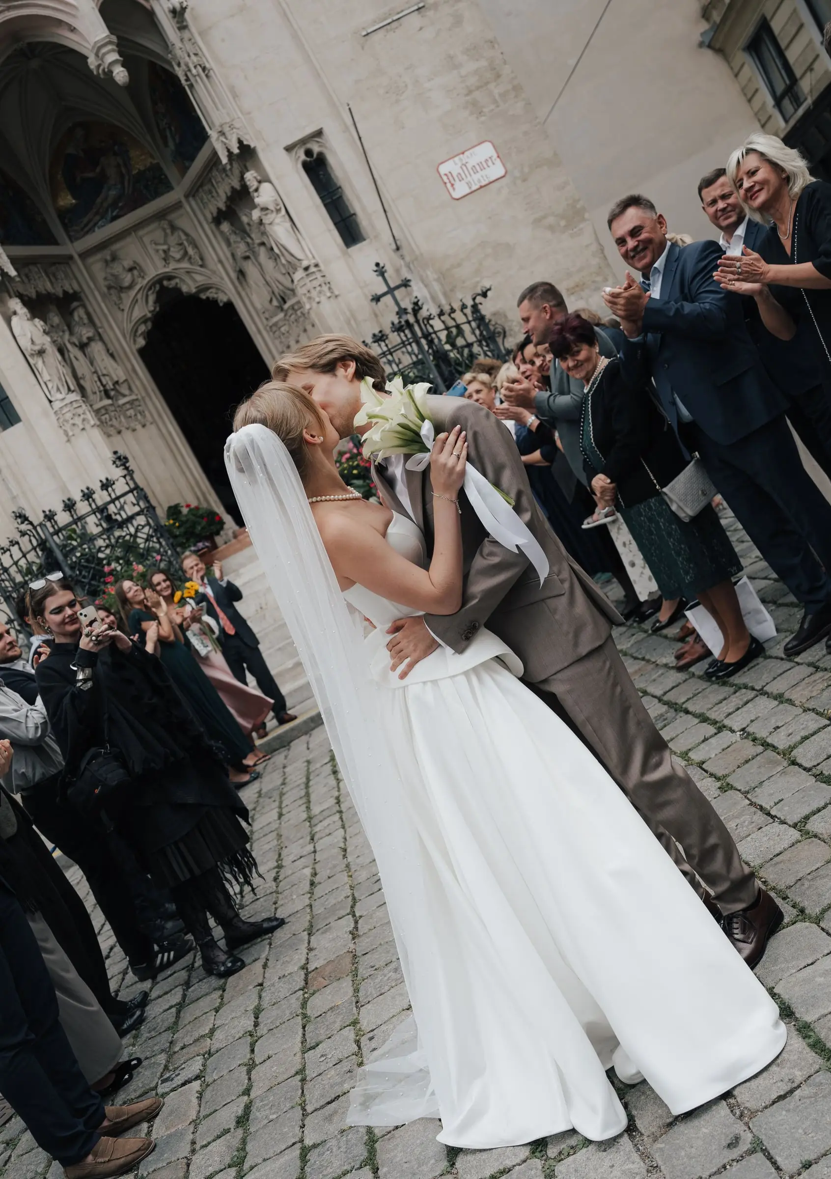 Newlyweds kissing outside Maria am Gestade as guests applaud