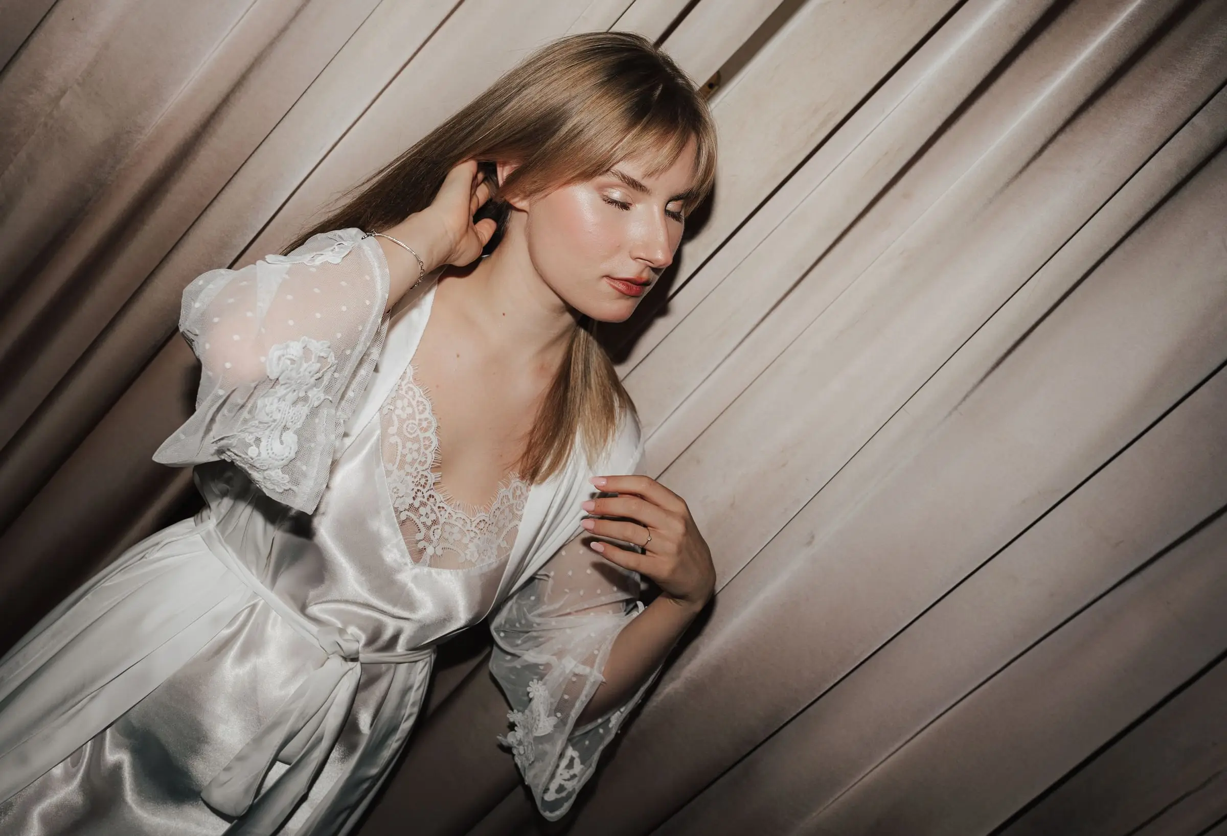 Bride in a silk robe getting ready, light falling through the blinds