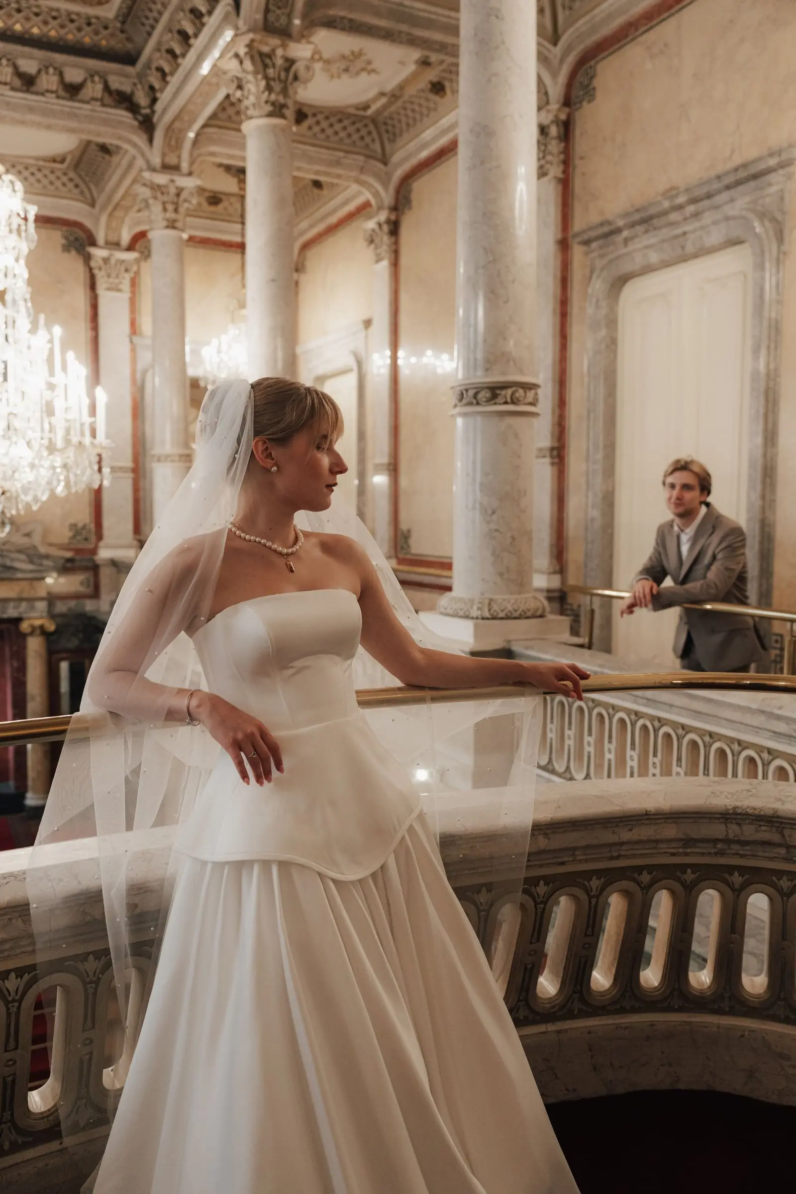 Bride on the grand staircase balcony, the groom waiting below