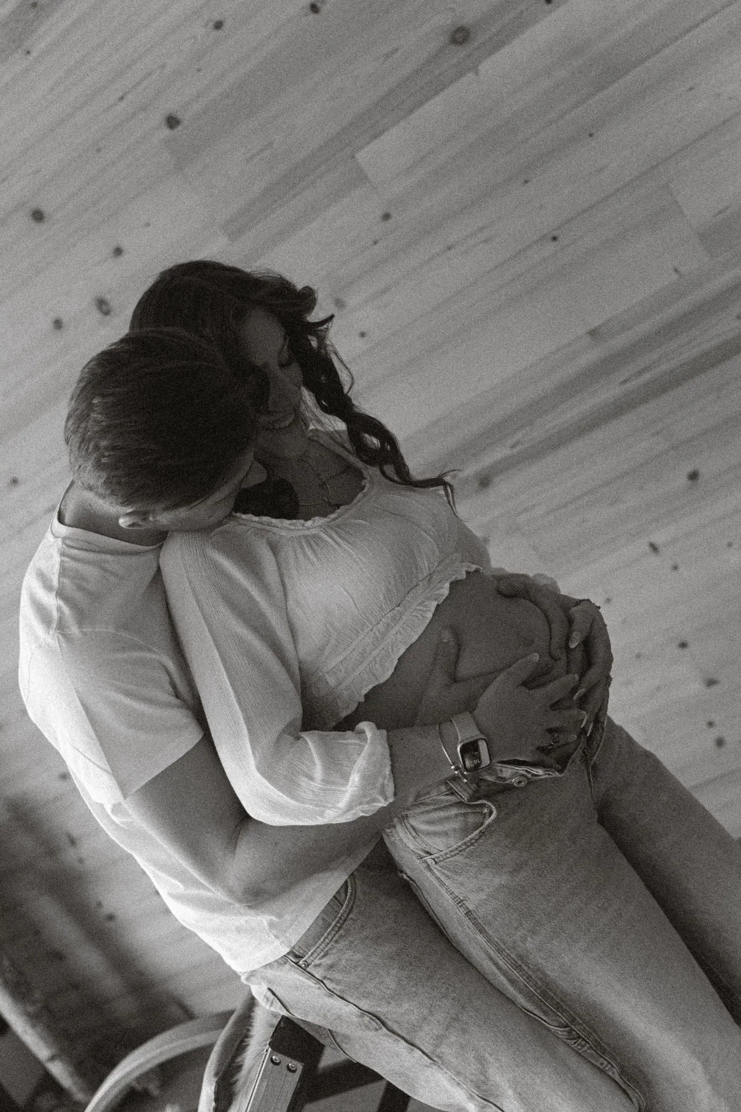 Black and white photo of the couple embracing on a wooden floor