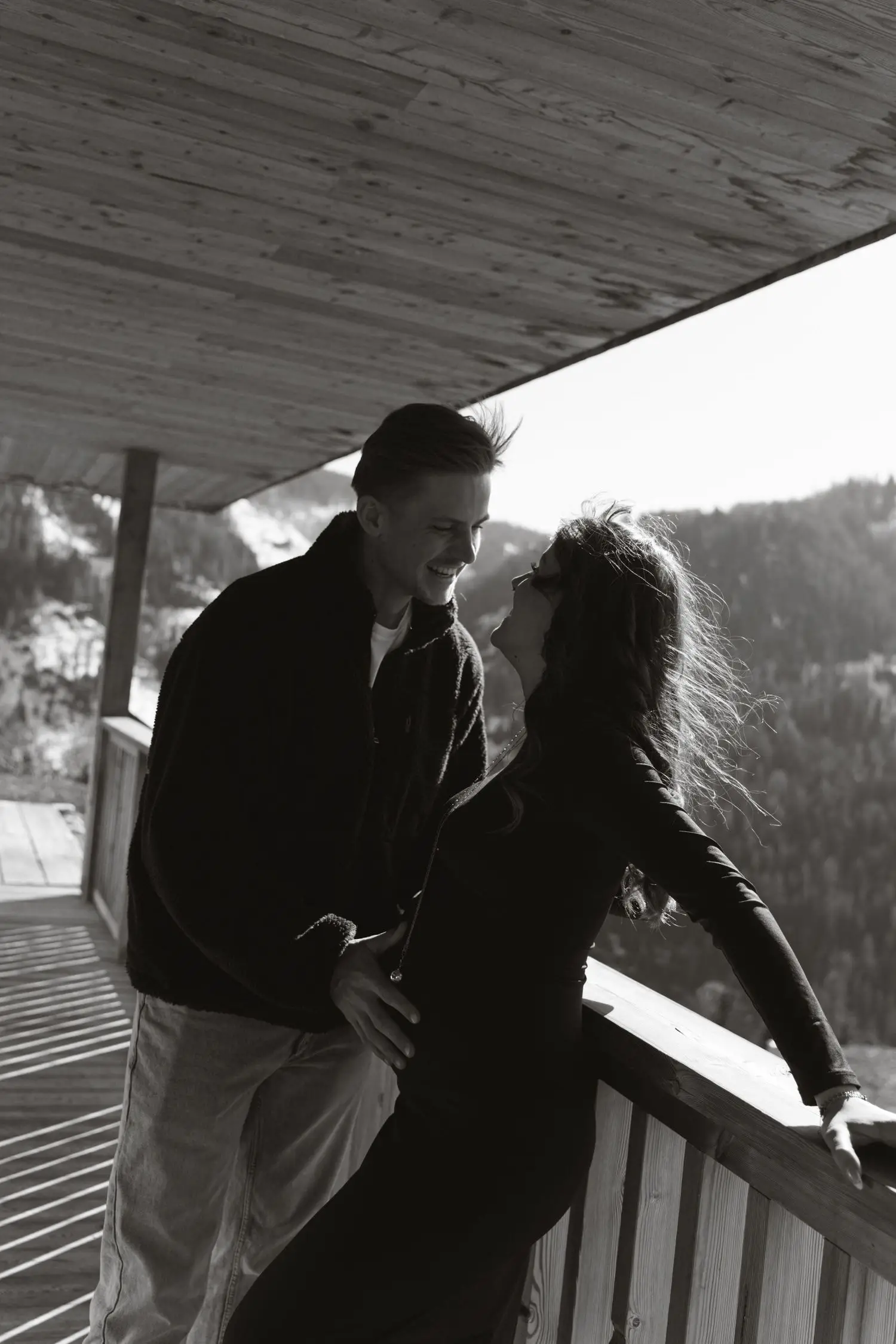 Black and white photo of the couple close together on a chalet balcony