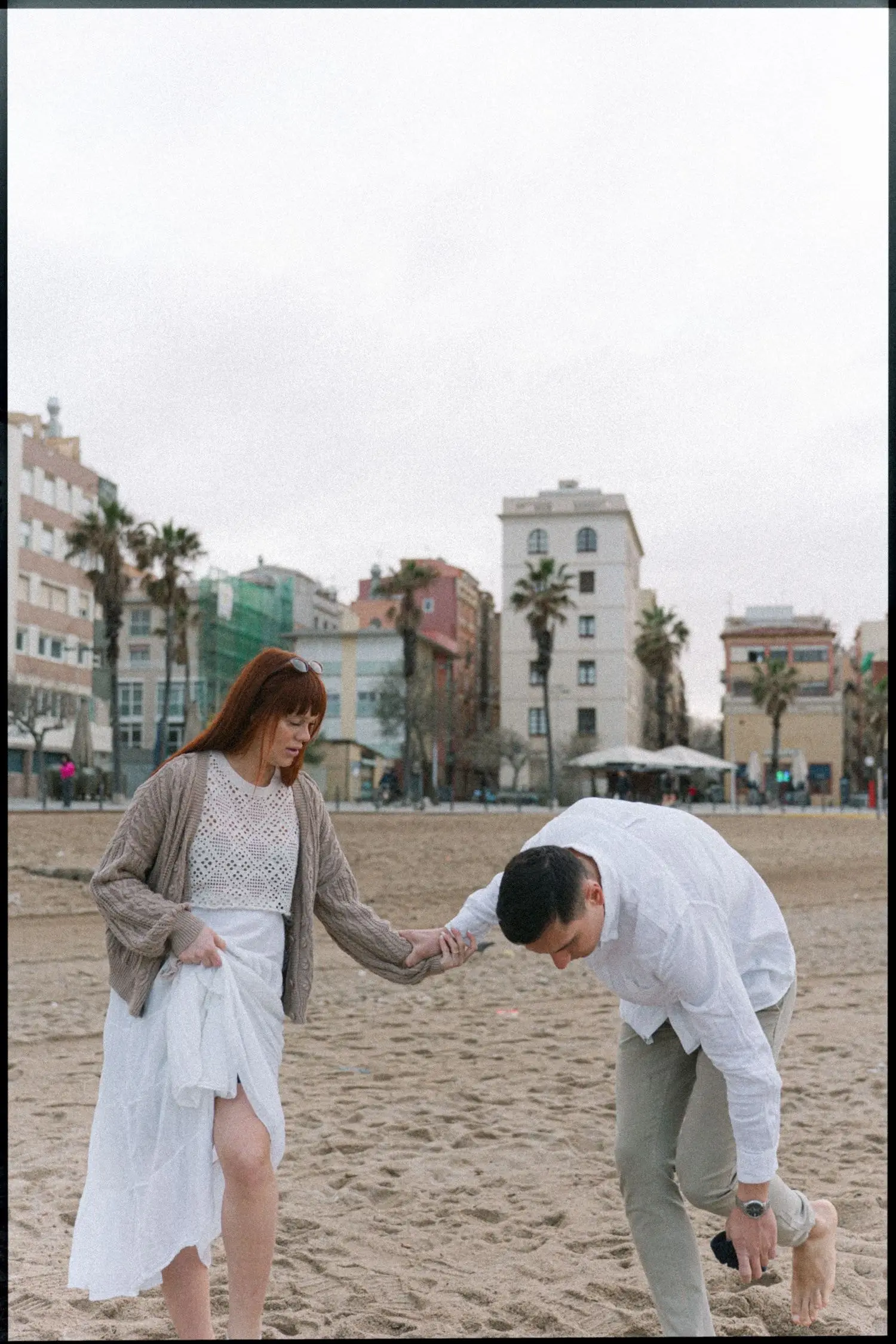 Couple playing on a city beach lined with palm trees, on film