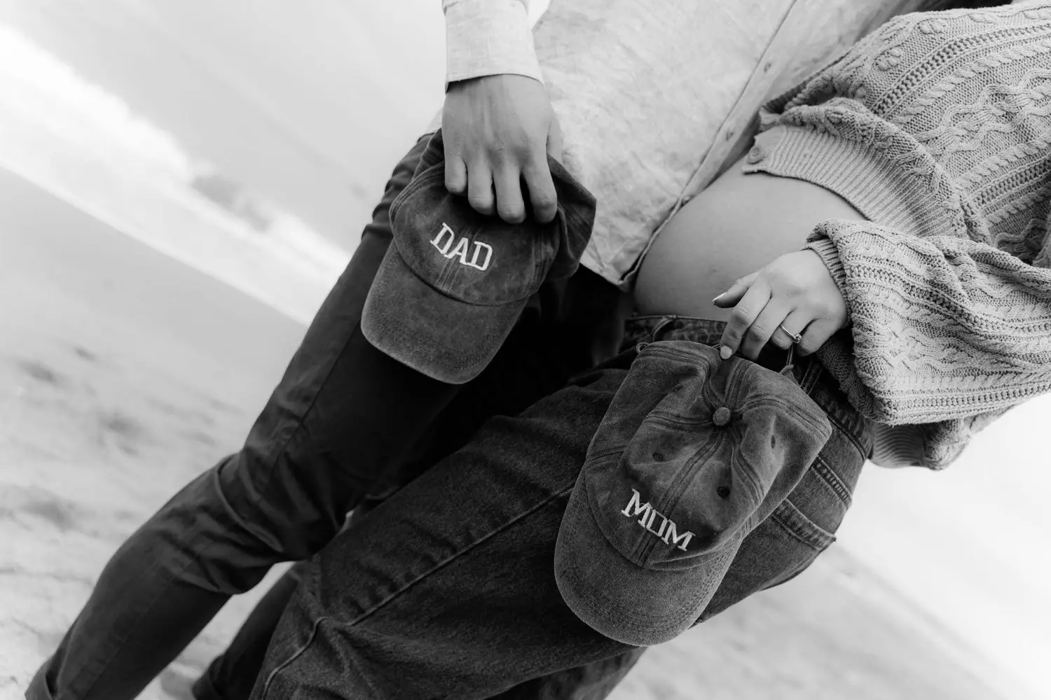 Black and white detail of MUM and DAD caps held against the belly
