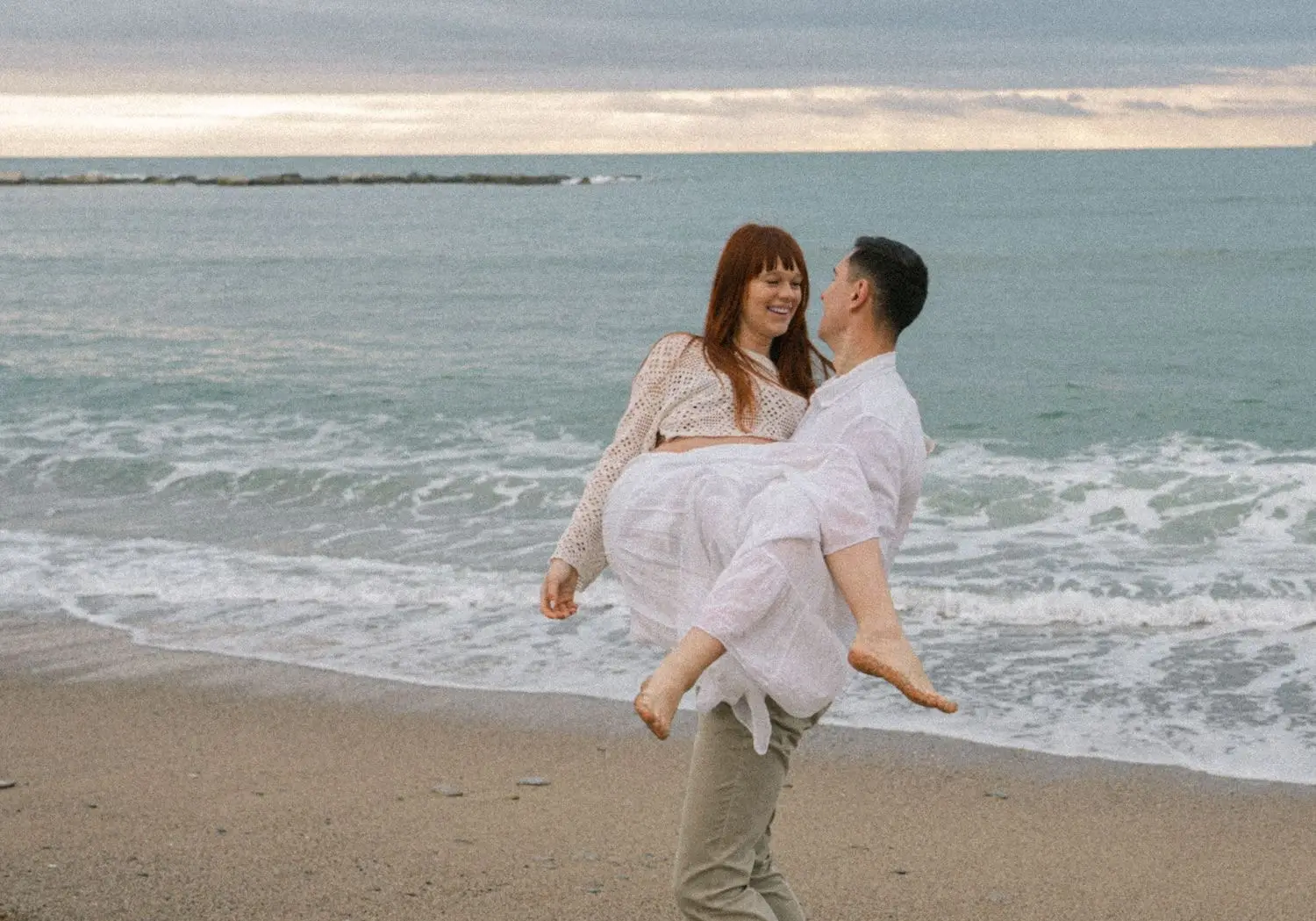 He carries the mother-to-be along the shoreline