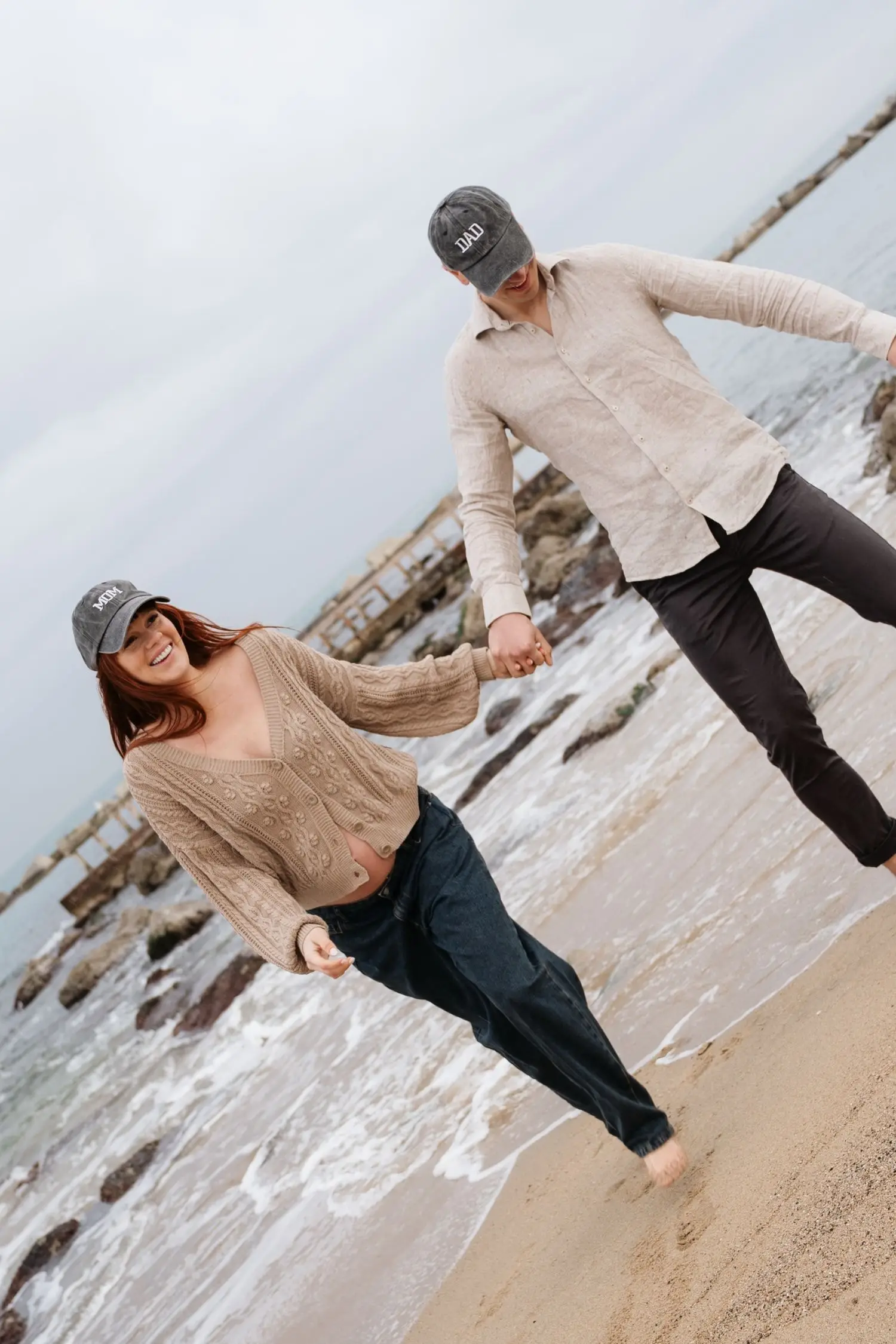 Couple in caps dancing hand in hand on the beach