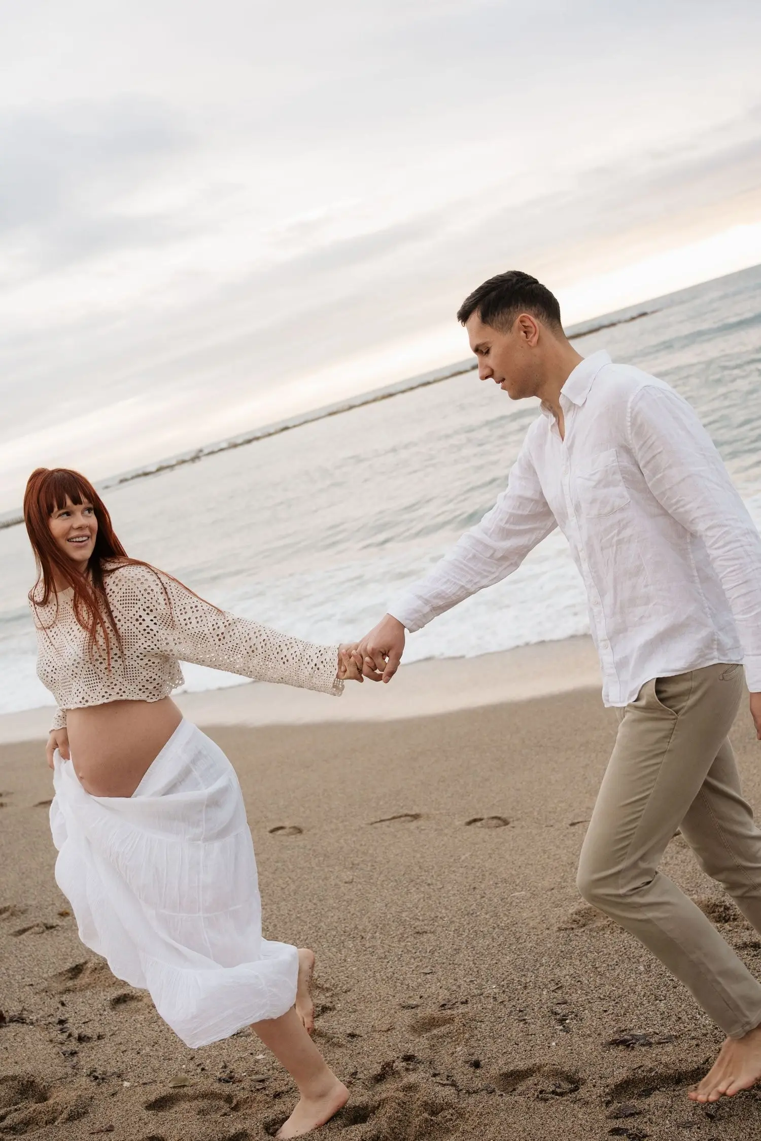 Couple running hand in hand along the beach, laughing