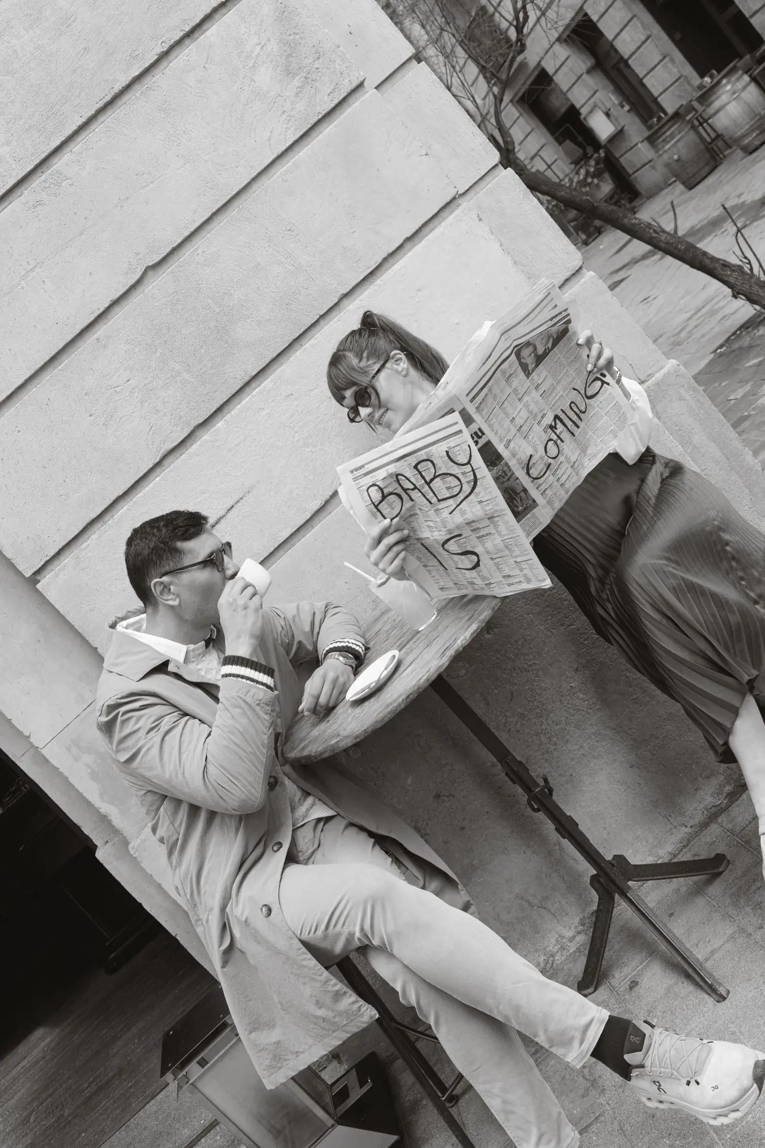 Black and white photo of the couple reading a newspaper announcing the baby