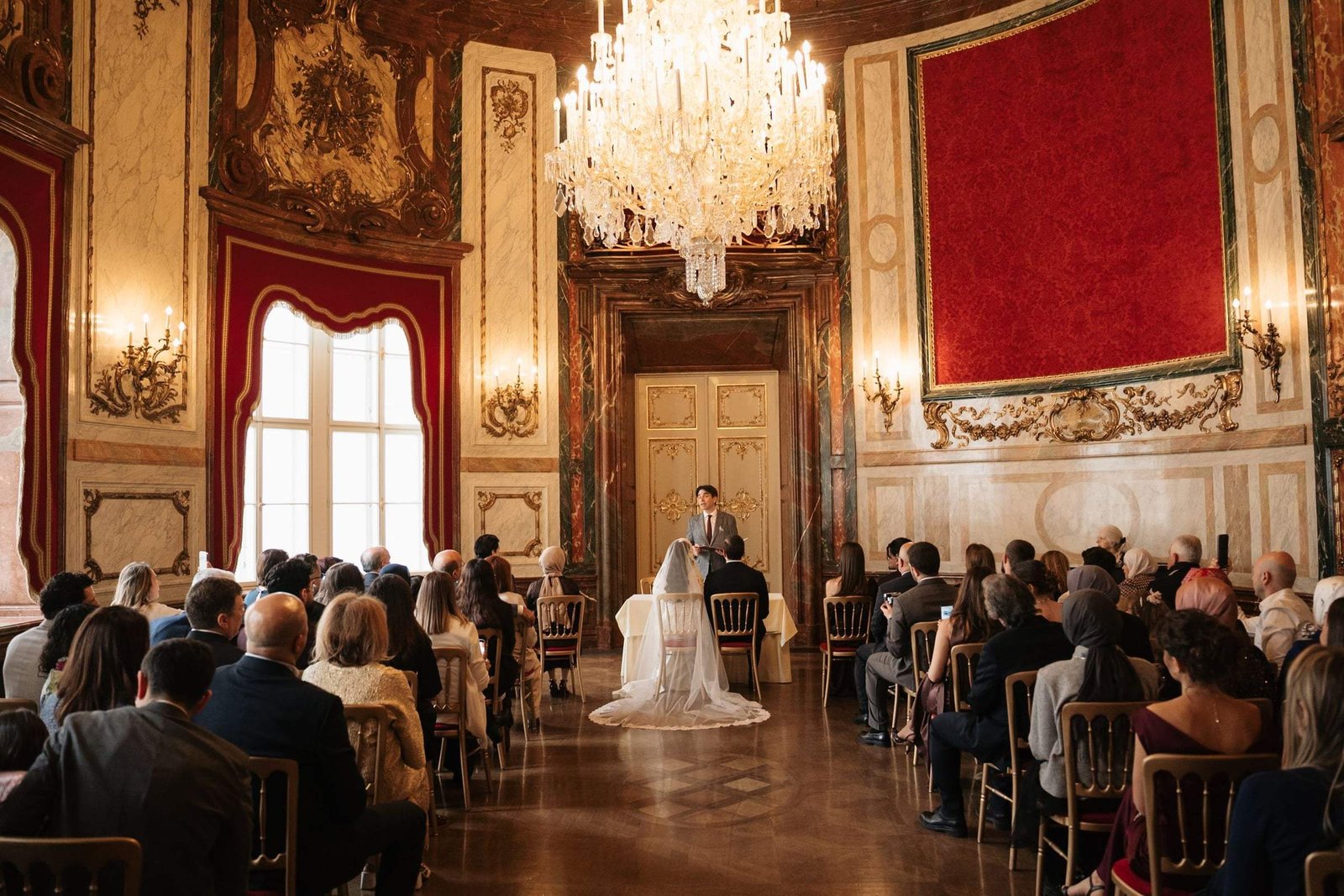 Civil wedding ceremony in a red and gold baroque hall at Palais Daun-Kinsky