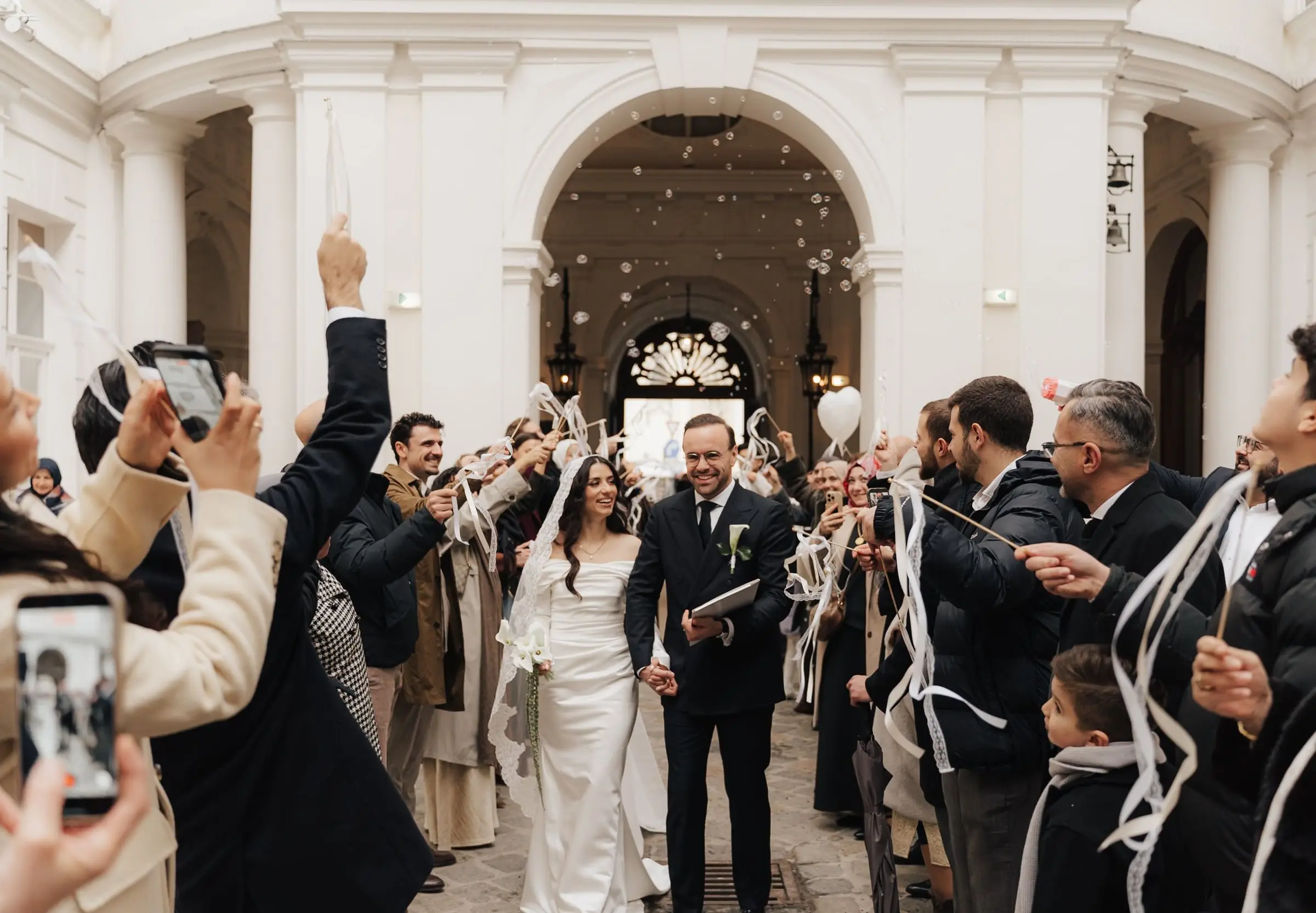 Newlyweds walking out through the palace courtyard as guests throw ribbons
