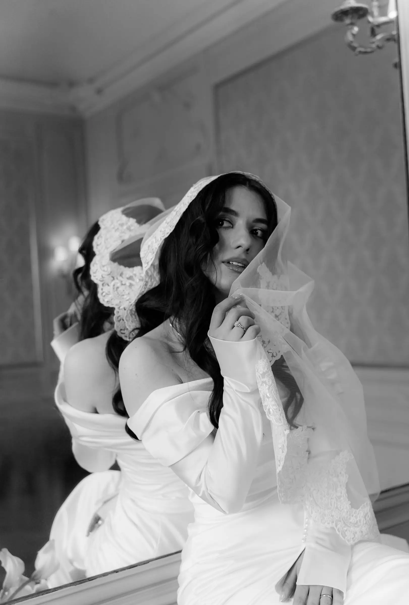 Black and white photo of the bride adjusting her lace veil