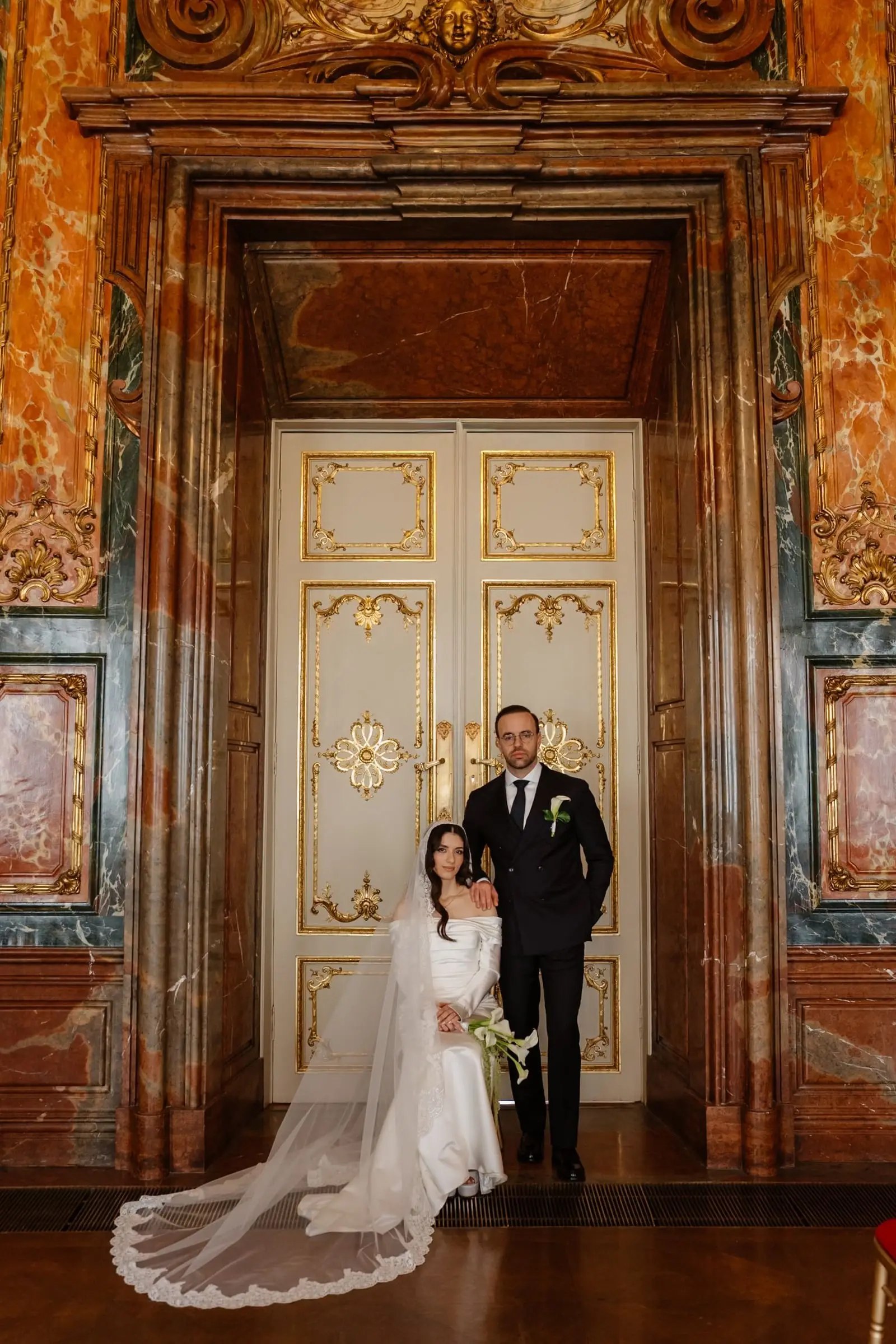 Couple standing at a gilded door in a marble hall of Palais Daun-Kinsky