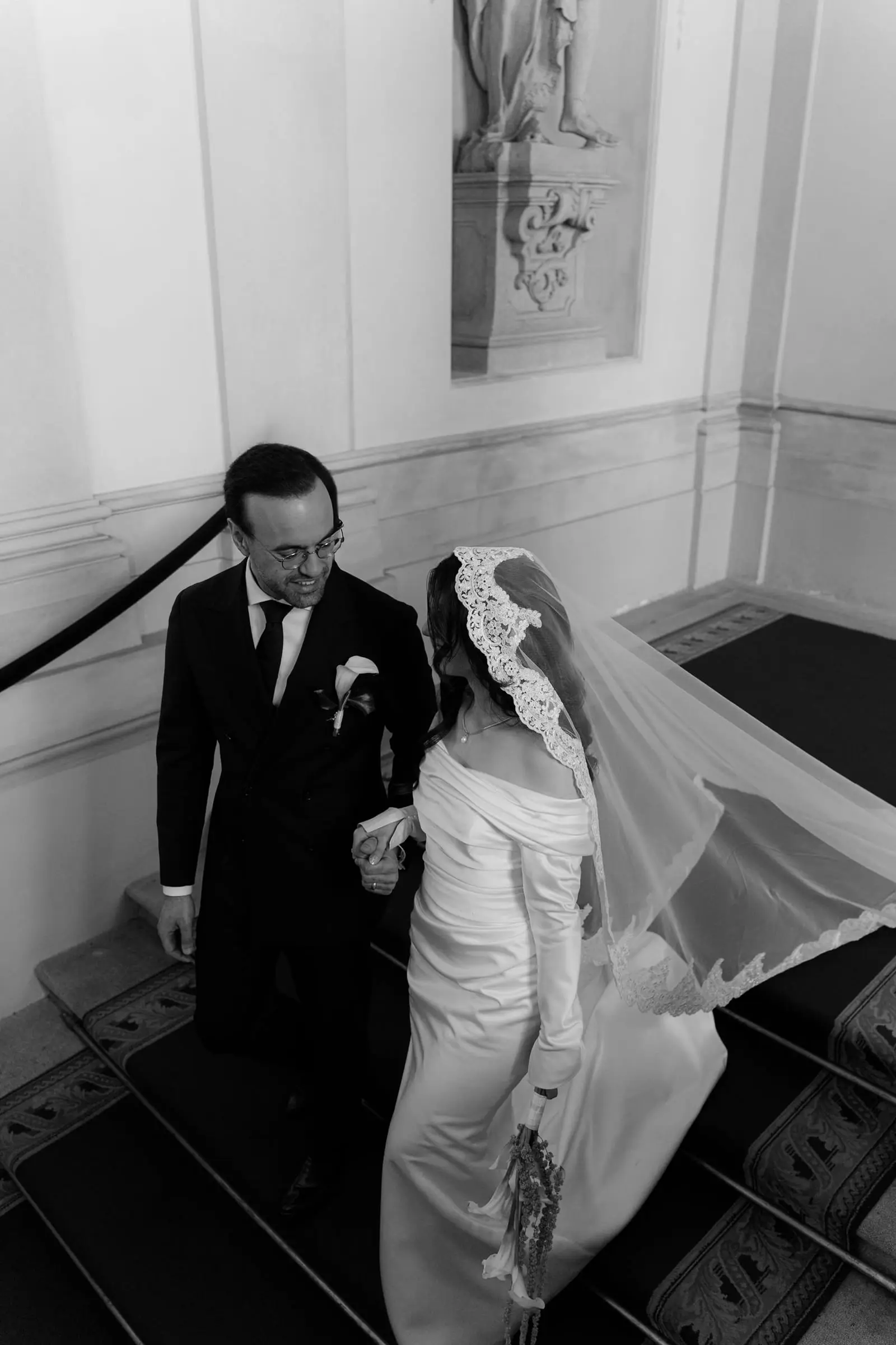 Black and white photo of the father leading the bride down the stairs