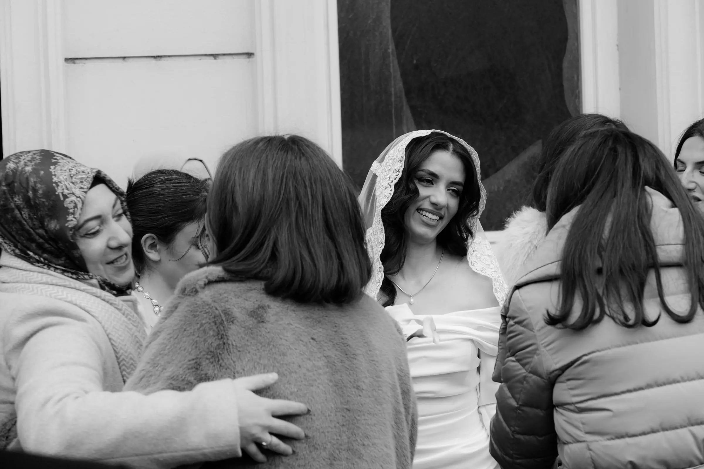 Black and white photo of the bride greeted by her family