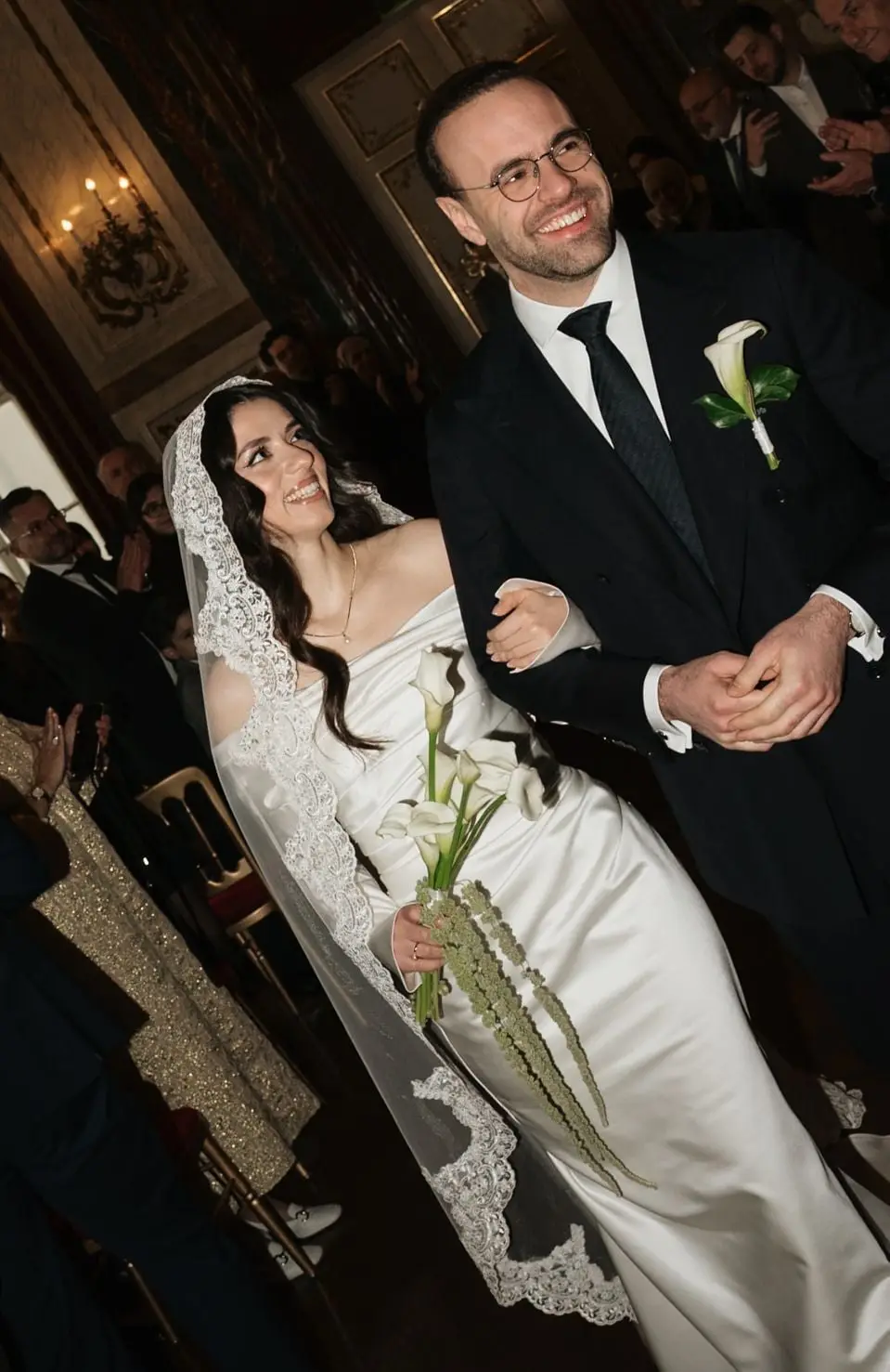 Couple walking arm in arm into the candlelit palace hall