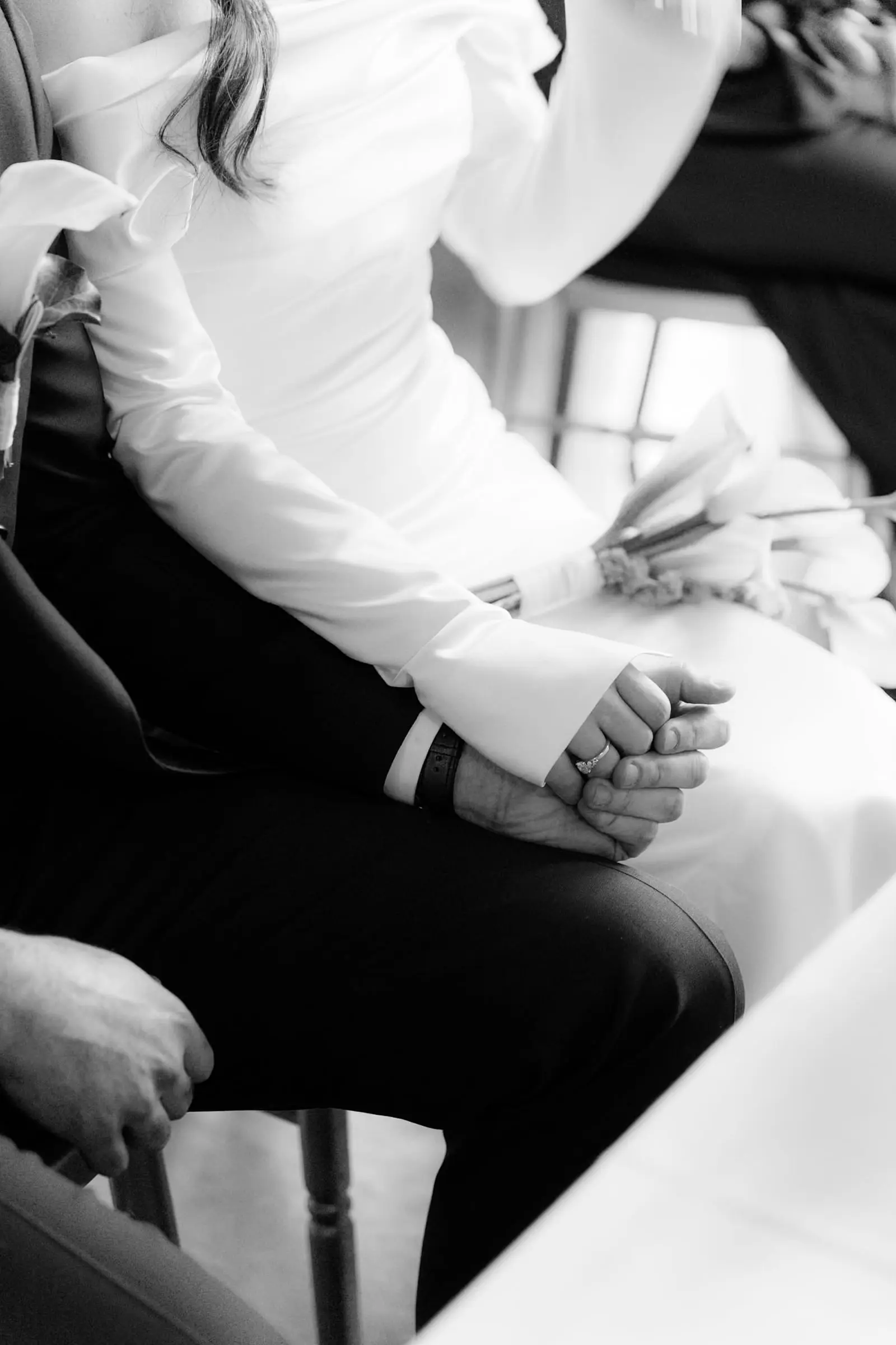 Black and white detail of the couple holding hands during the ceremony