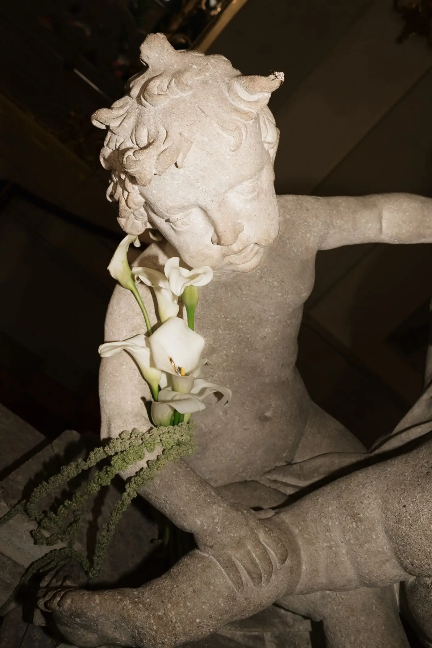 Calla lily bouquet resting on a marble cherub sculpture