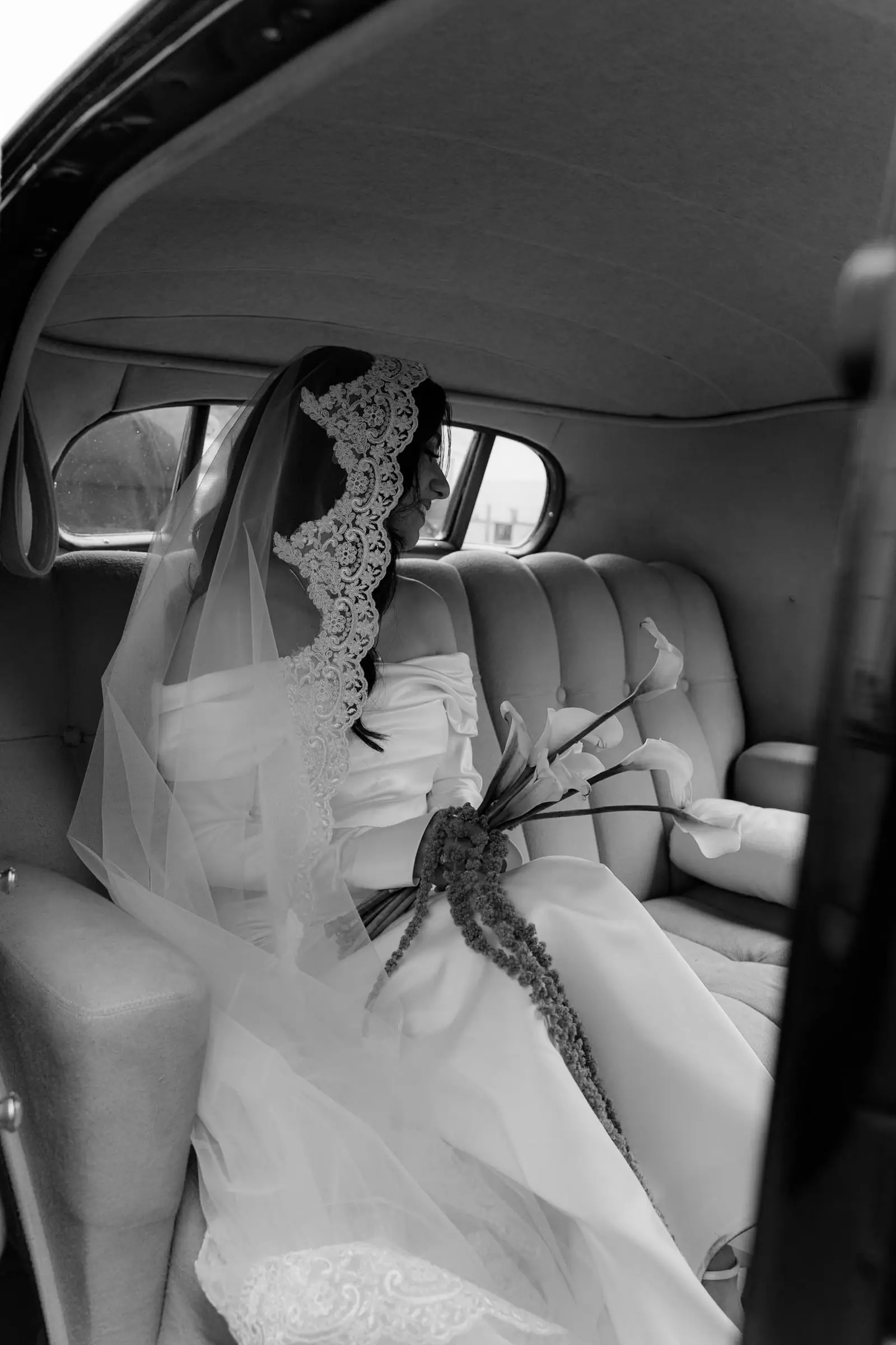 Black and white photo of the bride sitting in the vintage car