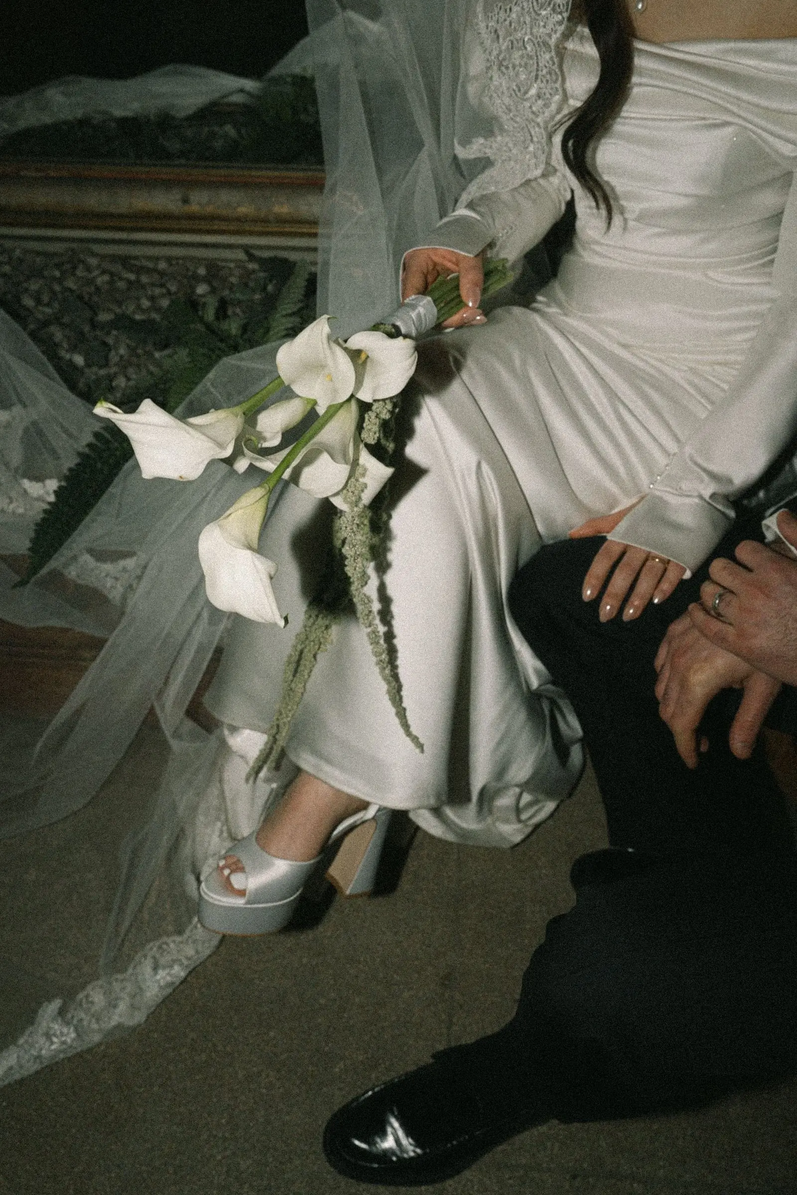 Detail of the bride's platform shoes, calla bouquet and satin gown
