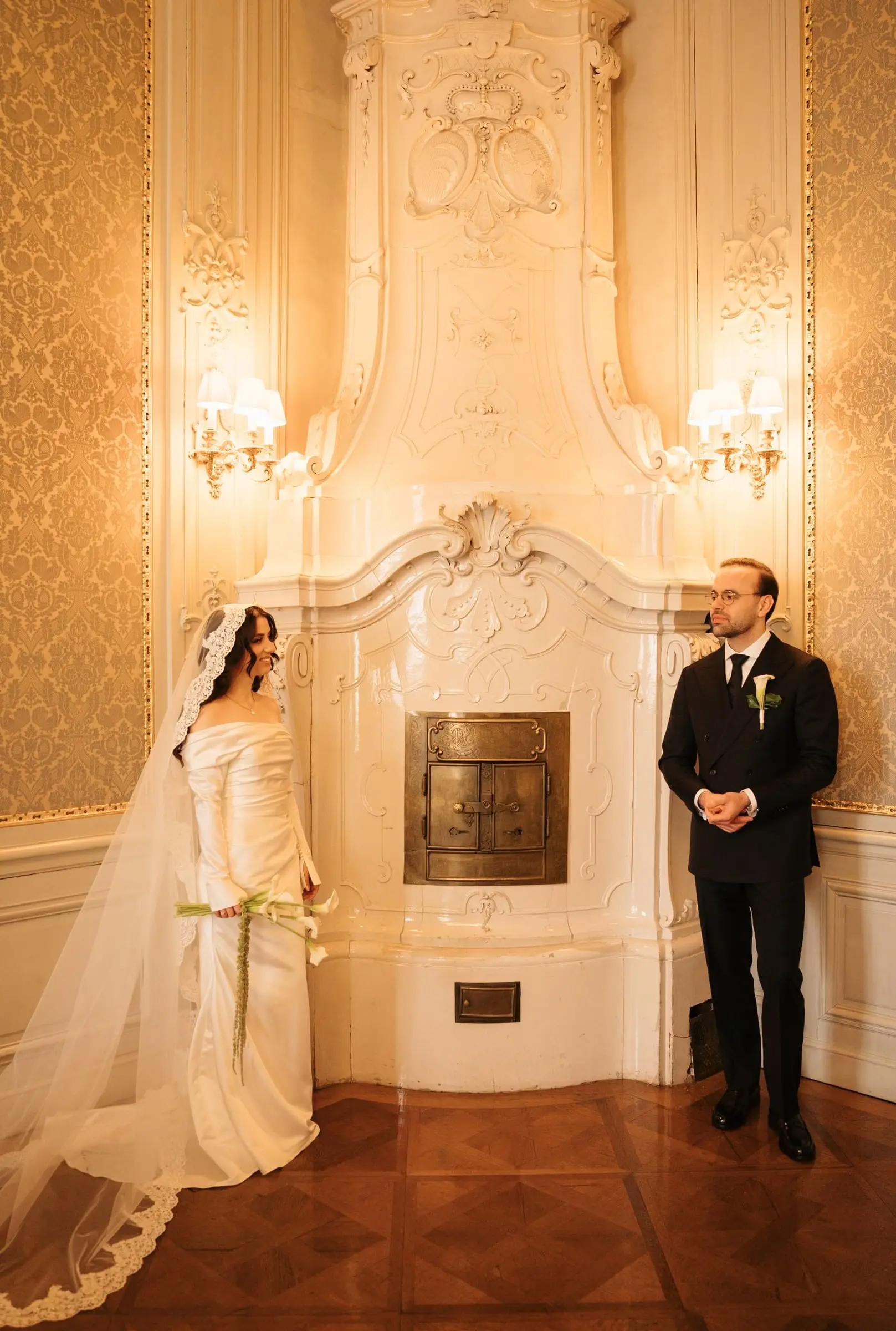 Couple beside a white baroque tiled stove in the palace