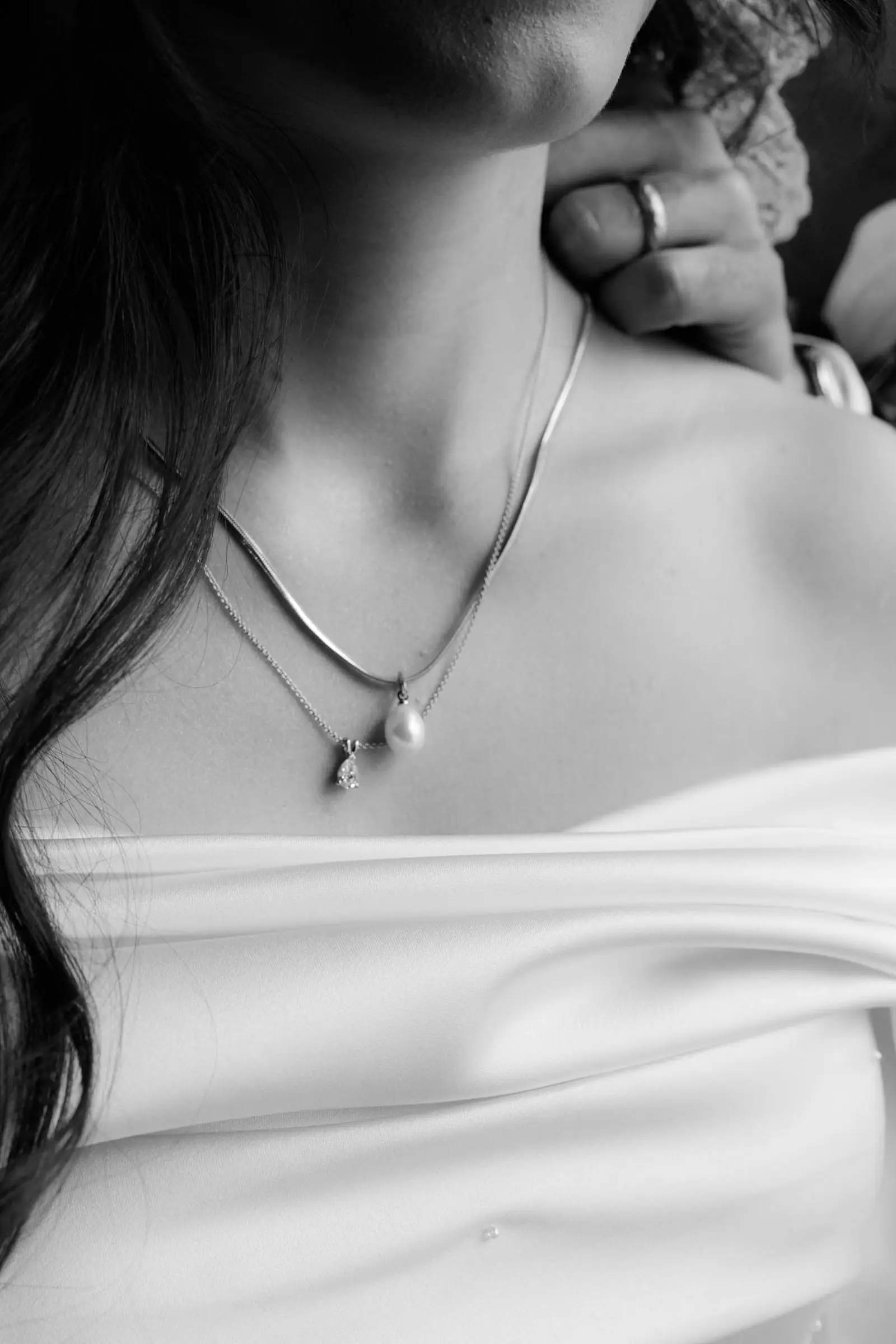 Black and white detail of the bride's necklace and bare shoulder