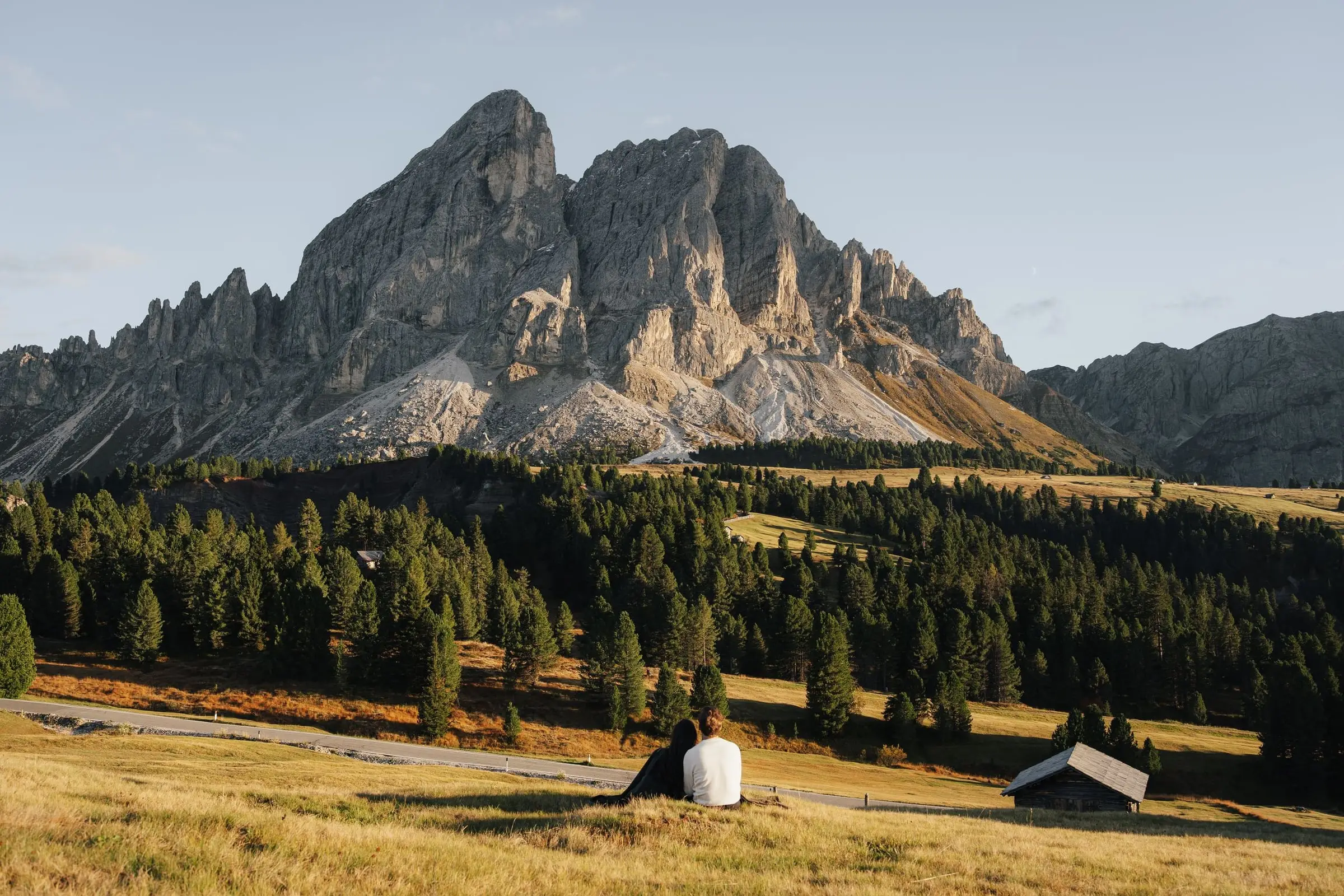 Couple sitting small in the meadow below the Sass de Putia