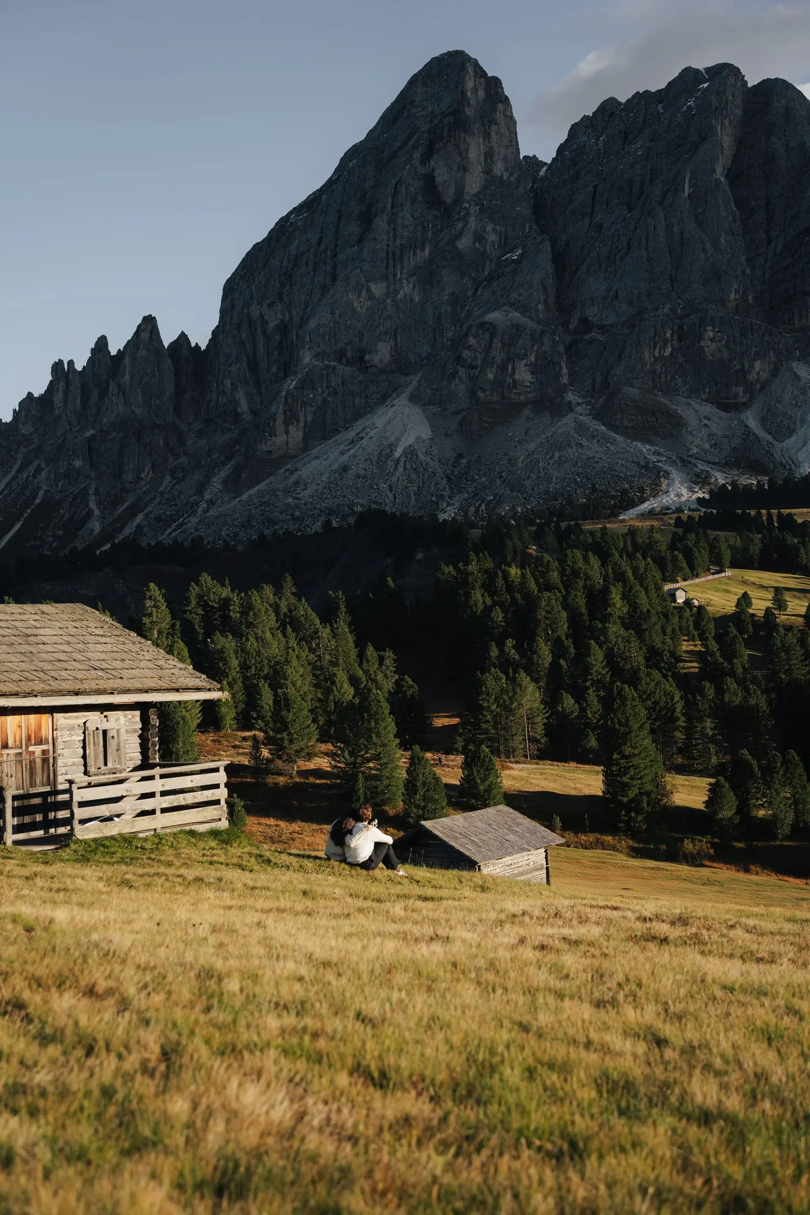 Couple beside a wooden hut below the jagged Sass de Putia