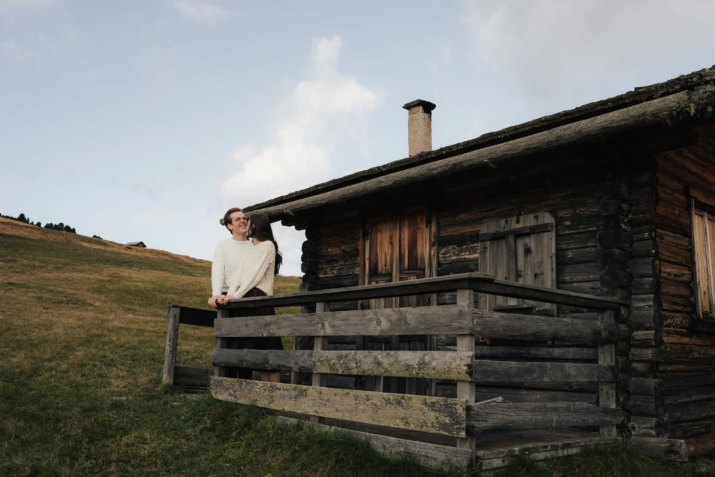 Couple on the fence of a wooden hut in the evening light