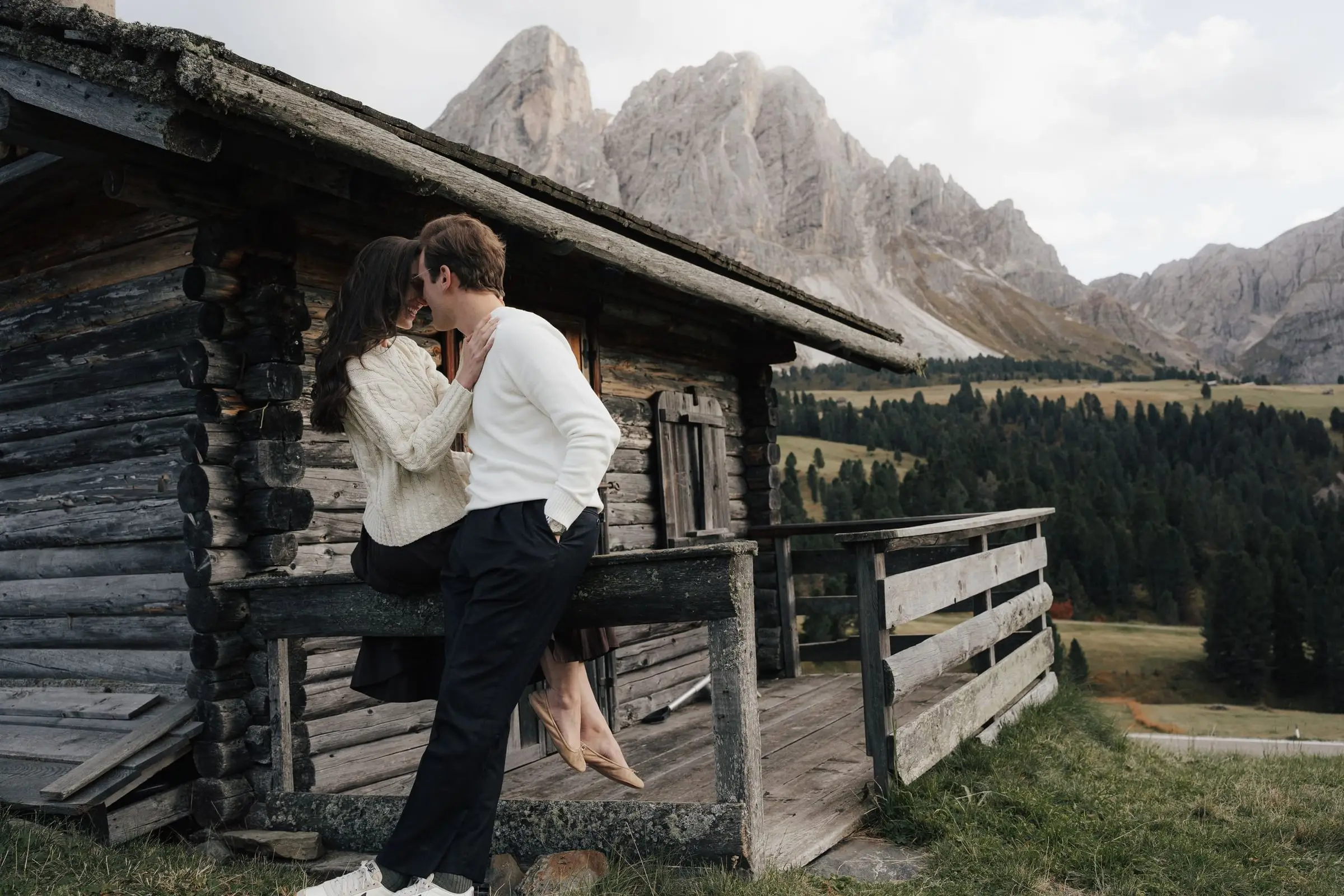 Couple kissing on the porch of a mountain hut at Passo delle Erbe