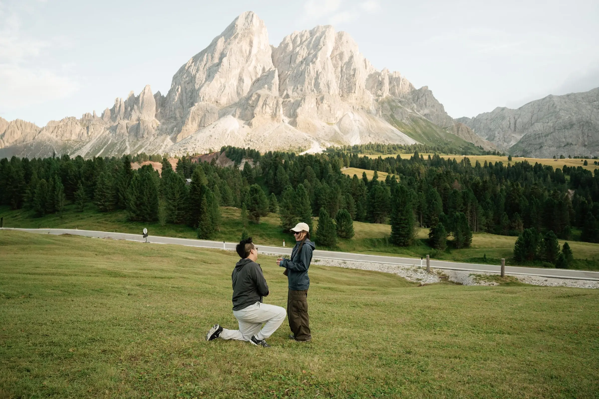 Man kneeling to propose in the meadow at Passo delle Erbe below the Sass de Putia