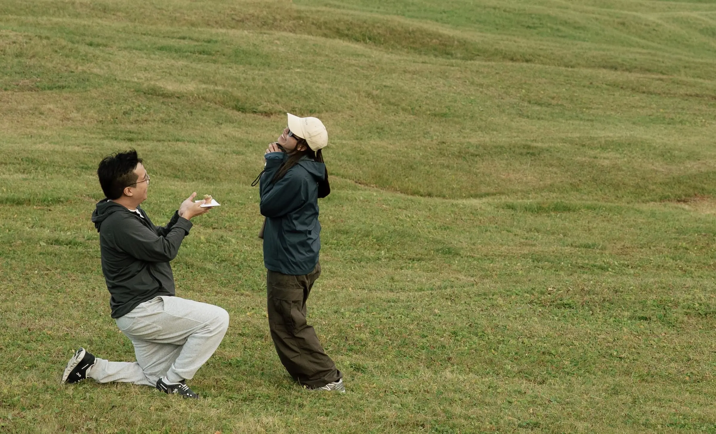 Surprised moment as he kneels with the ring in the green meadow