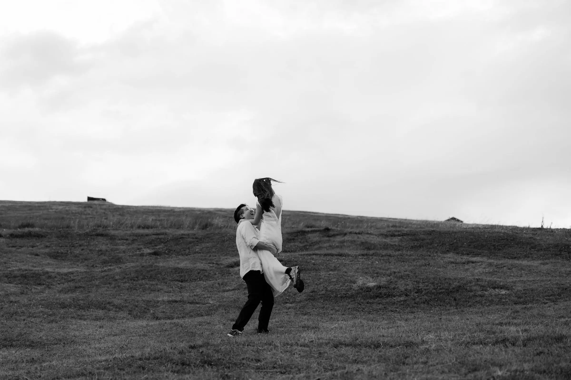 Black and white photo of the couple spinning in the meadow after the proposal