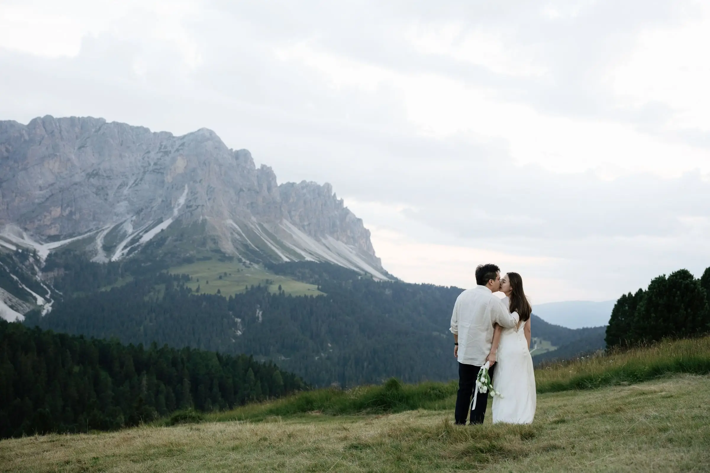 Couple kissing in the meadow with the Odle peaks behind