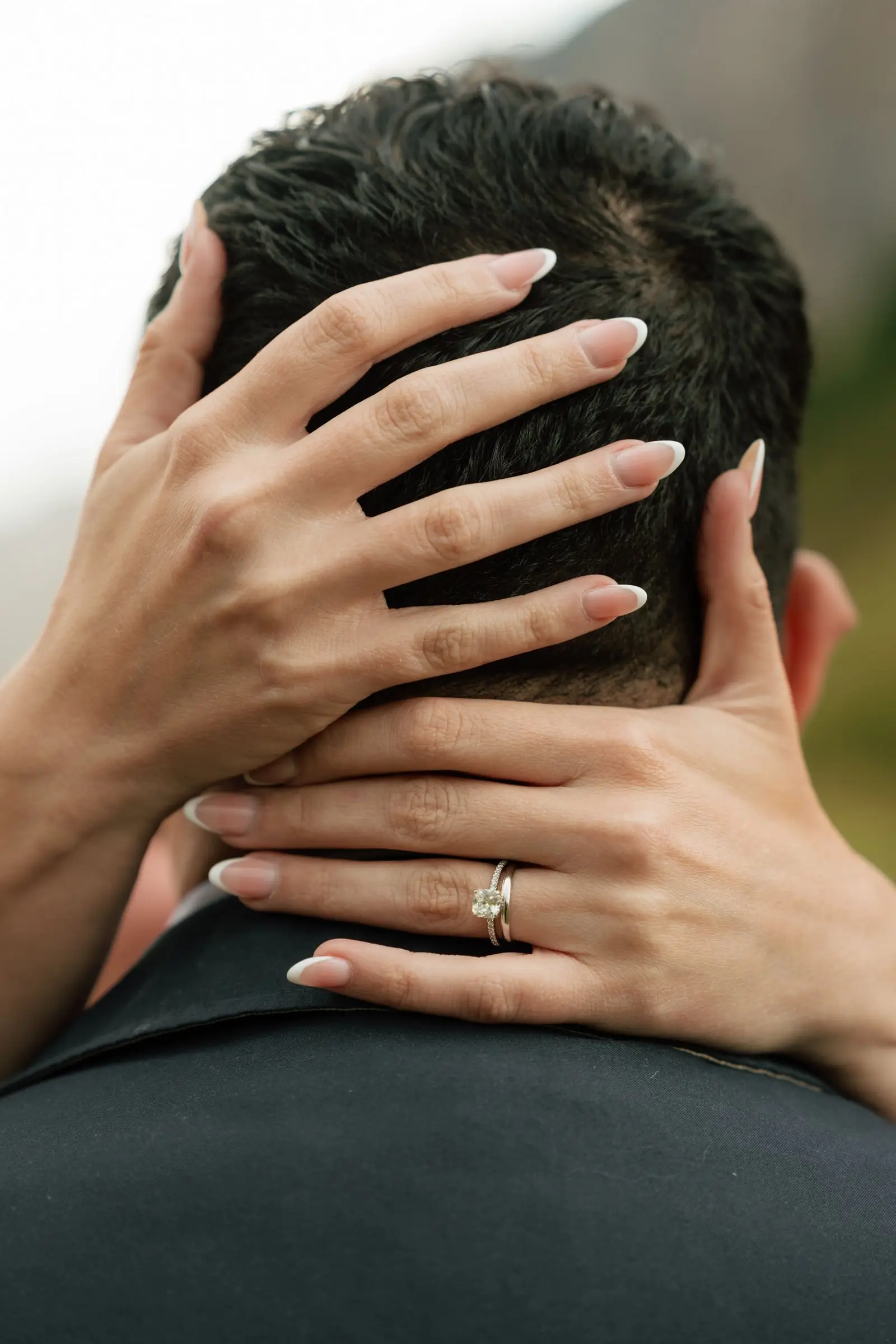 Her hands with wedding rings resting on the back of his neck