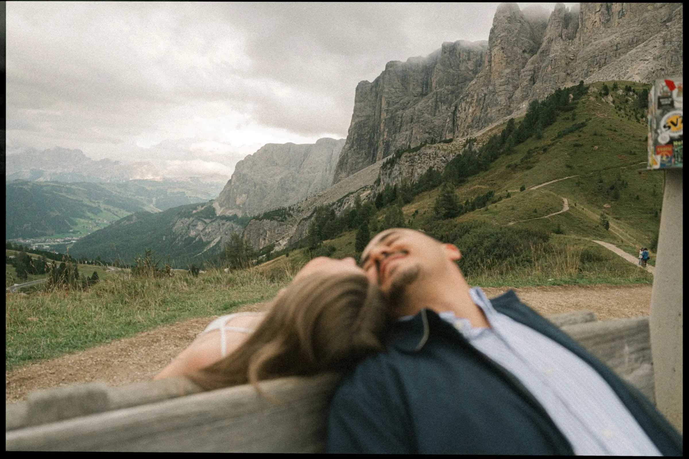 Couple resting their heads on a wooden bench above the valley, on film