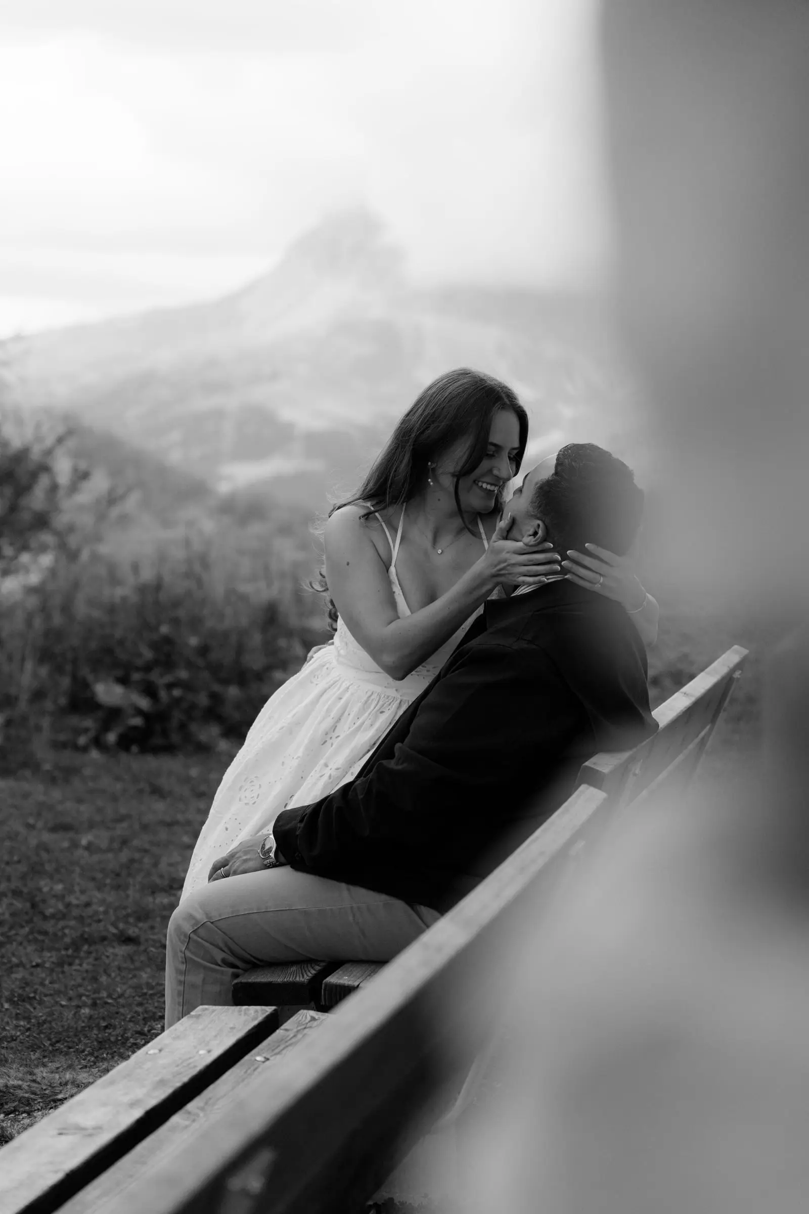 Black and white photo of the couple embracing on a bench