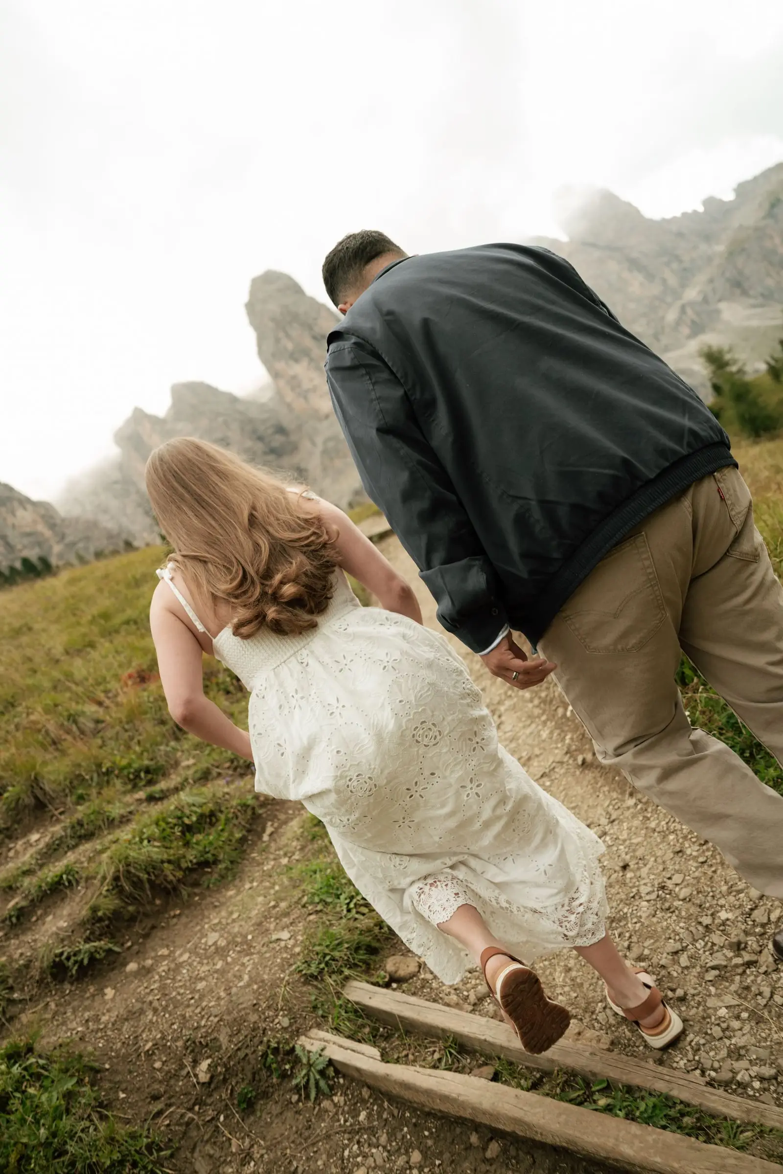 He leads her by the hand up a steep path