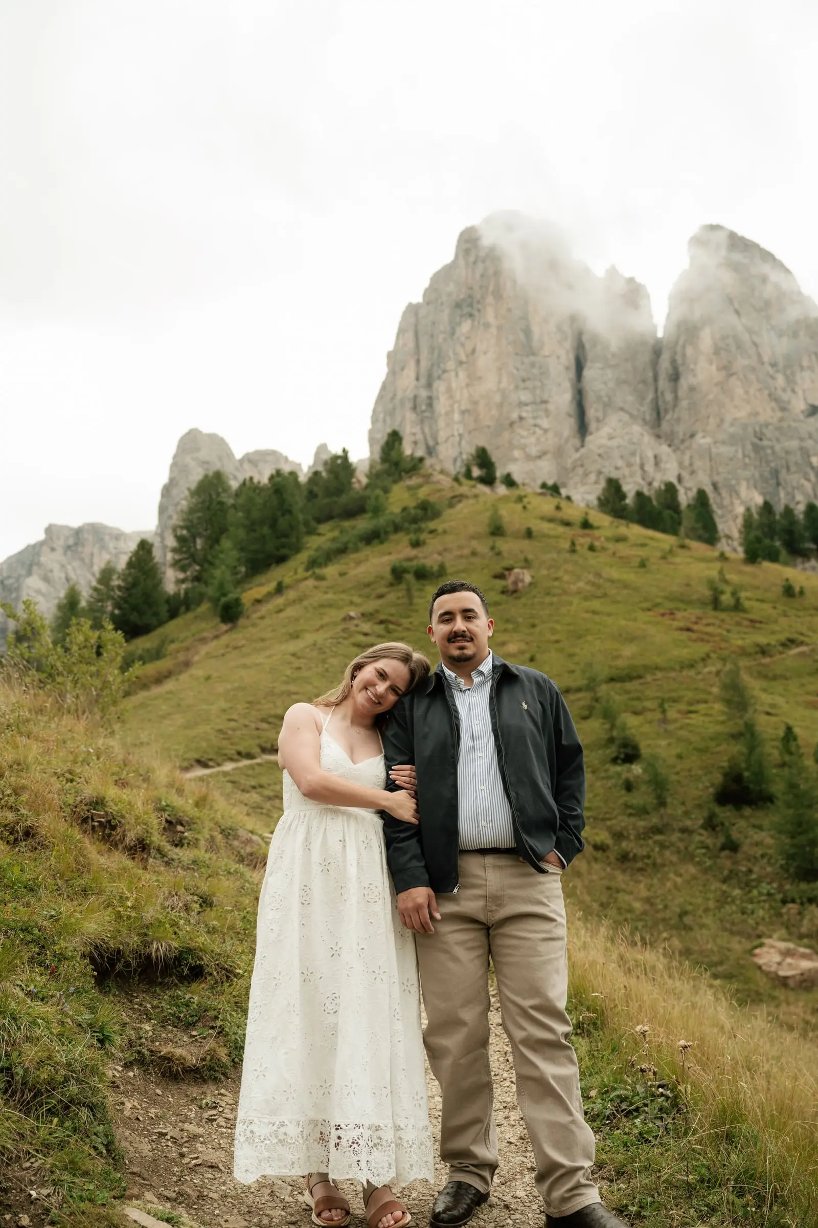 Couple standing together on the path, the Cir peaks in the clouds behind