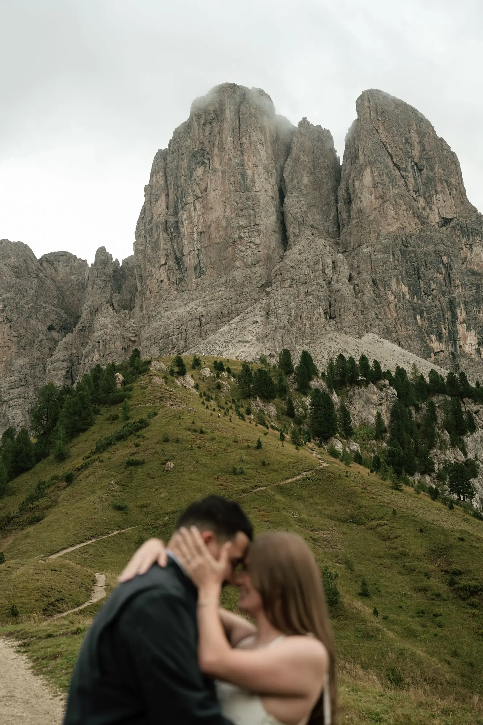 Couple kissing below the tall rock towers of Passo Gardena