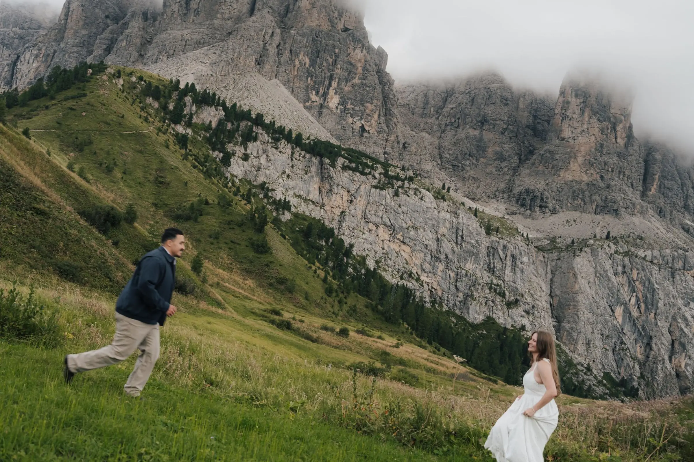 He runs towards her across the meadow below the rock walls