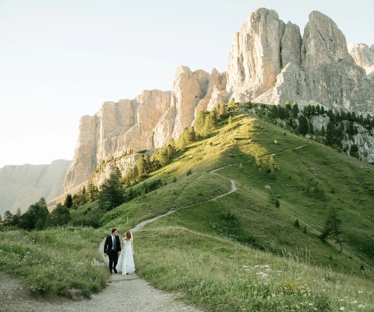 Couple walking a path towards the Sella group at Passo Gardena on a summer evening