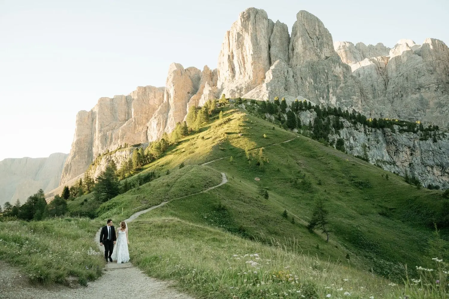 Couple walking a path towards the Sella group at Passo Gardena on a summer evening
