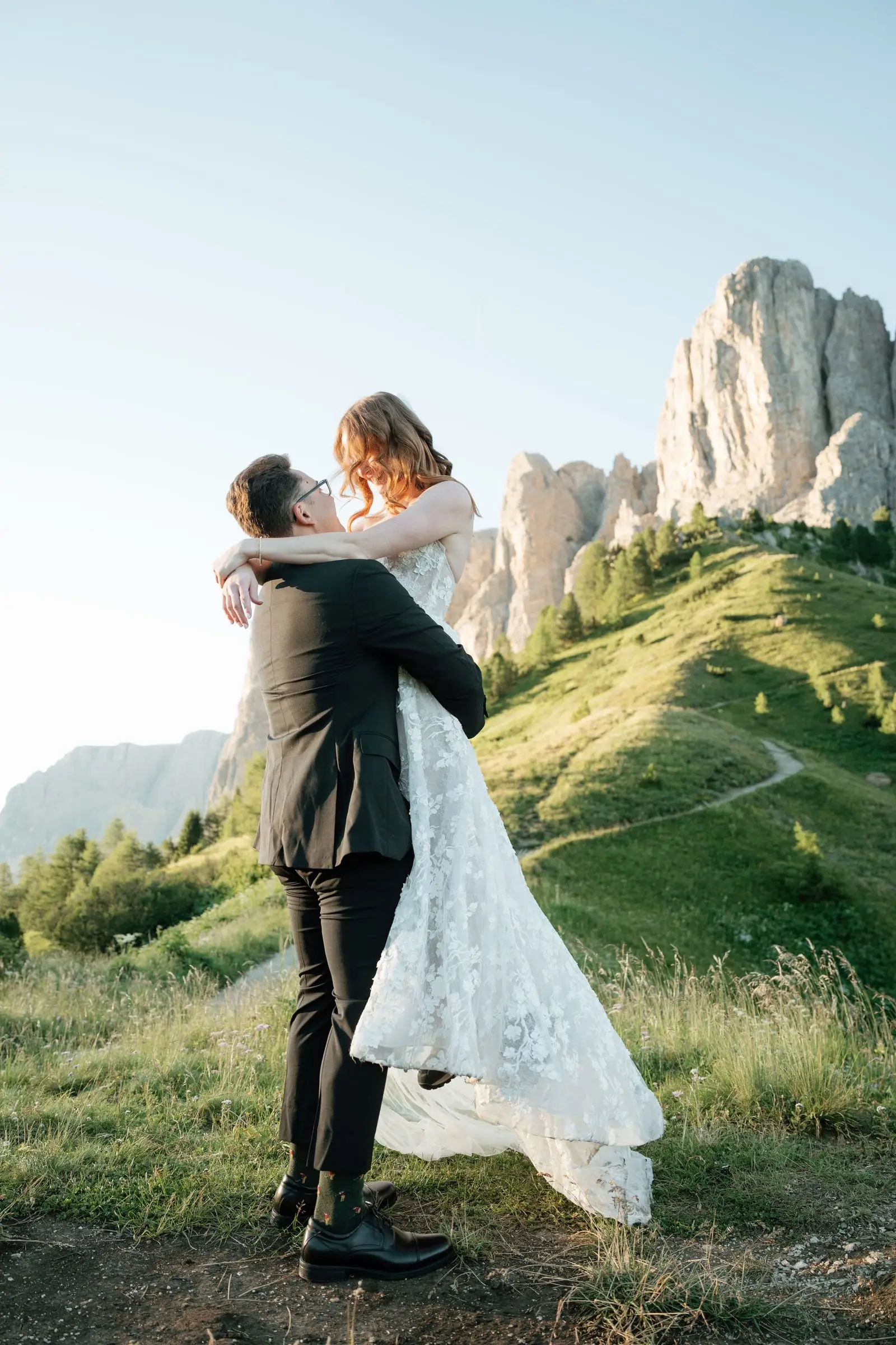 He lifts her in her lace gown, the rock towers behind them