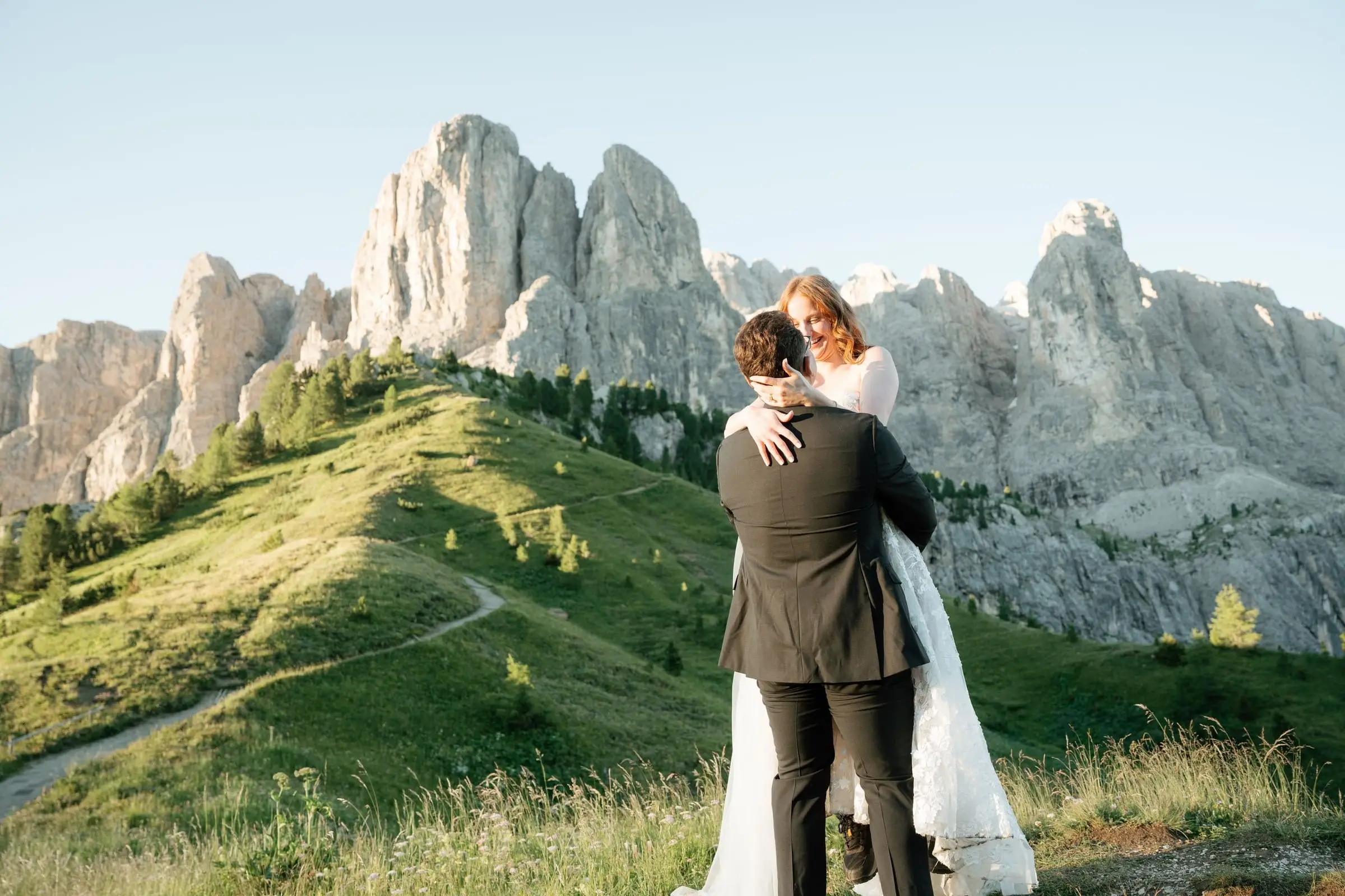 He holds her close on the hillside with the Sella group behind