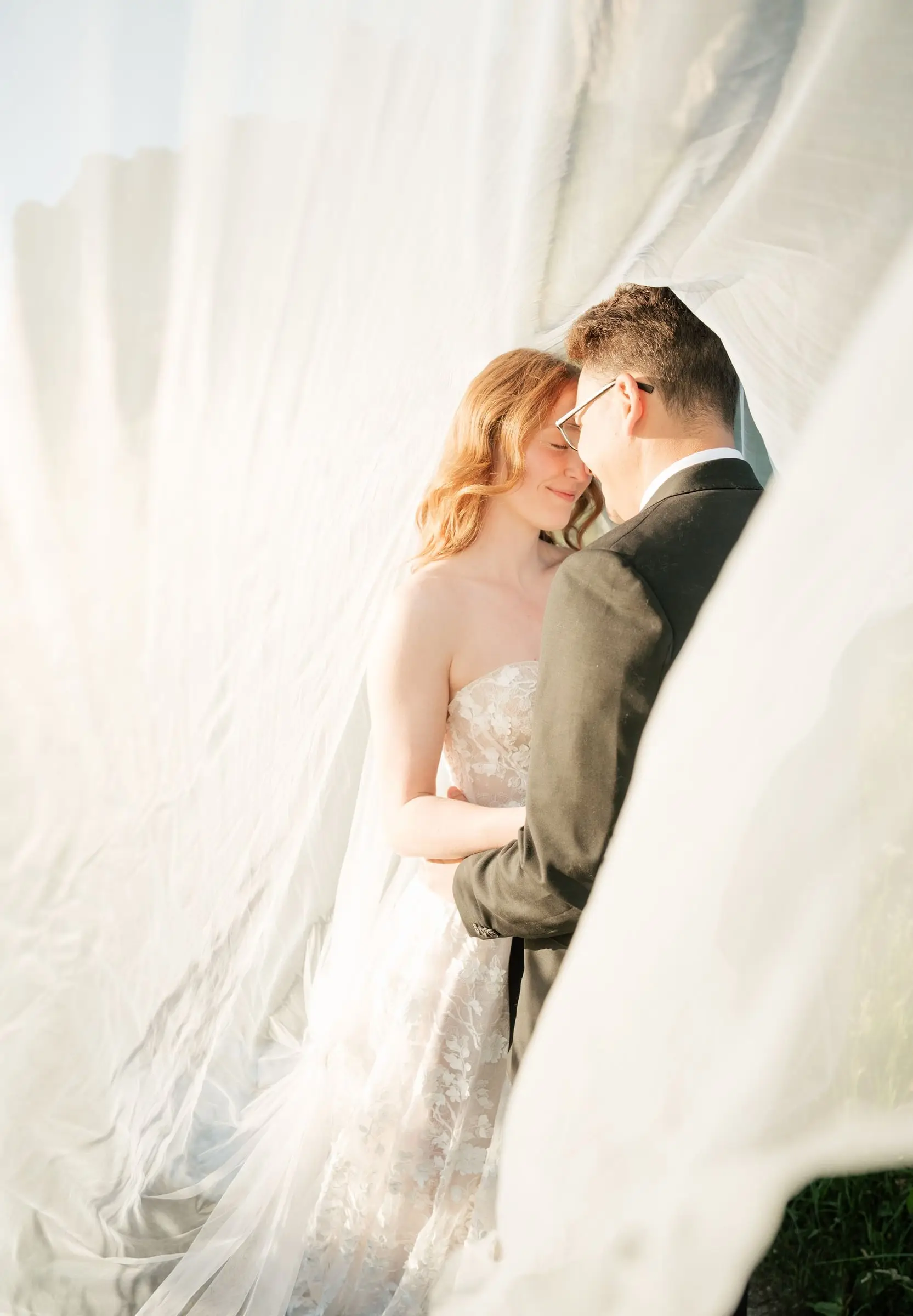 Couple wrapped in a long veil glowing in the evening light